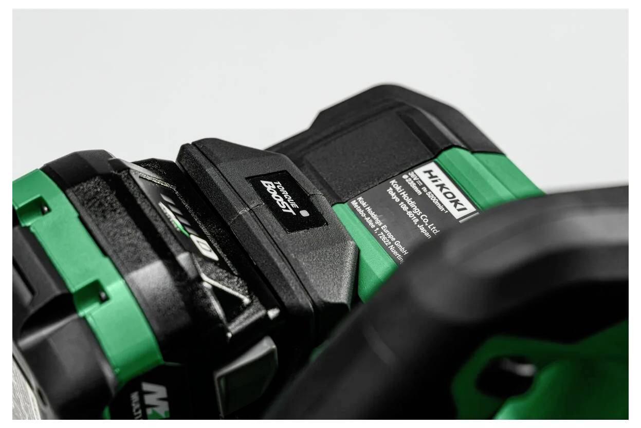 Detailní záběr baterie napájecího nástroje Hitachi v nabíječce, zobrazující značku 'Hikoki' a specifikace na štítku, zvýrazňující stav nabíjení.