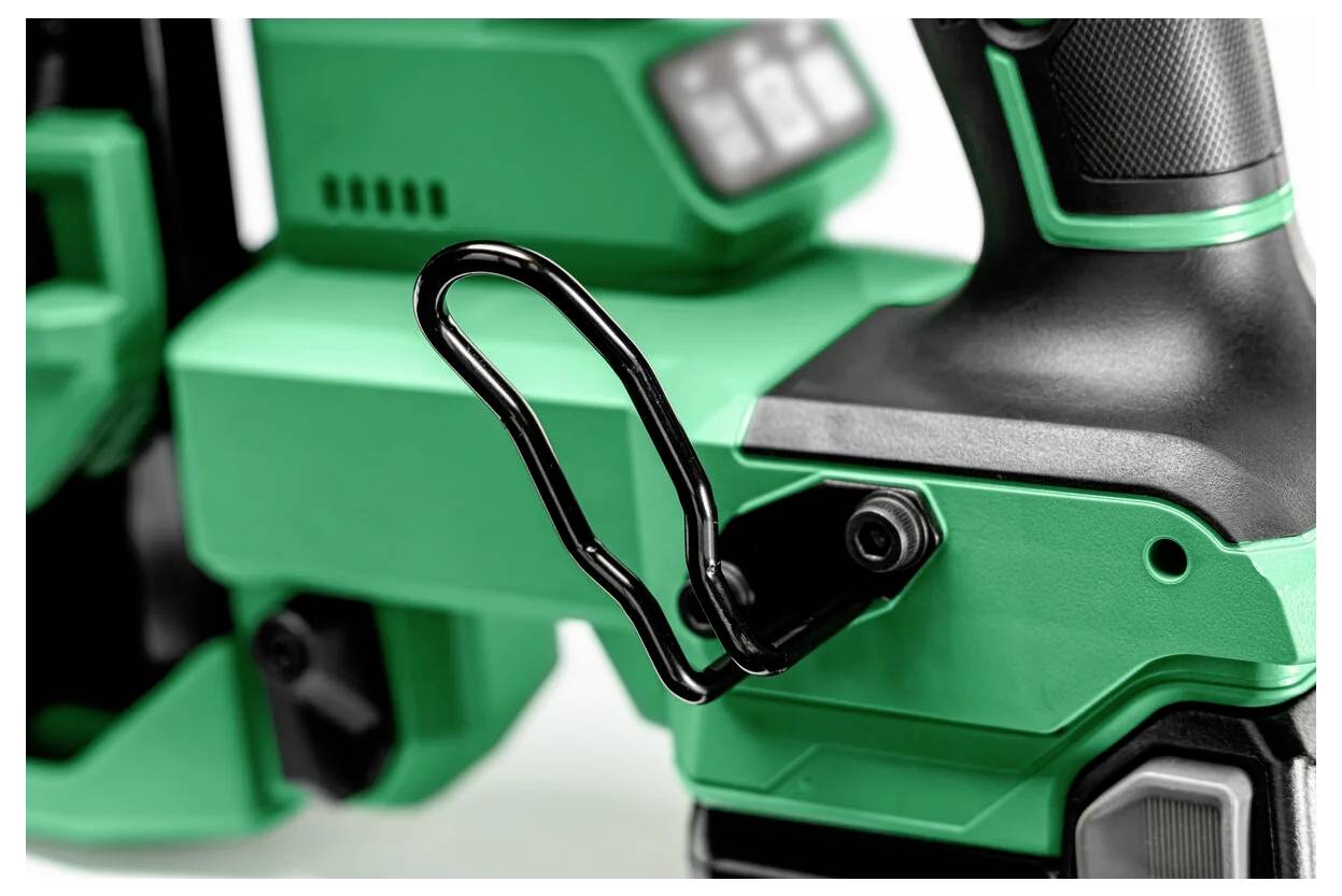 Detailní pohled na zeleno-černý elektrický nástroj, který je vybaven kovovým úchytem určeným pro zavěšení nebo přenášení. Nástroj působí moderně a robustně.