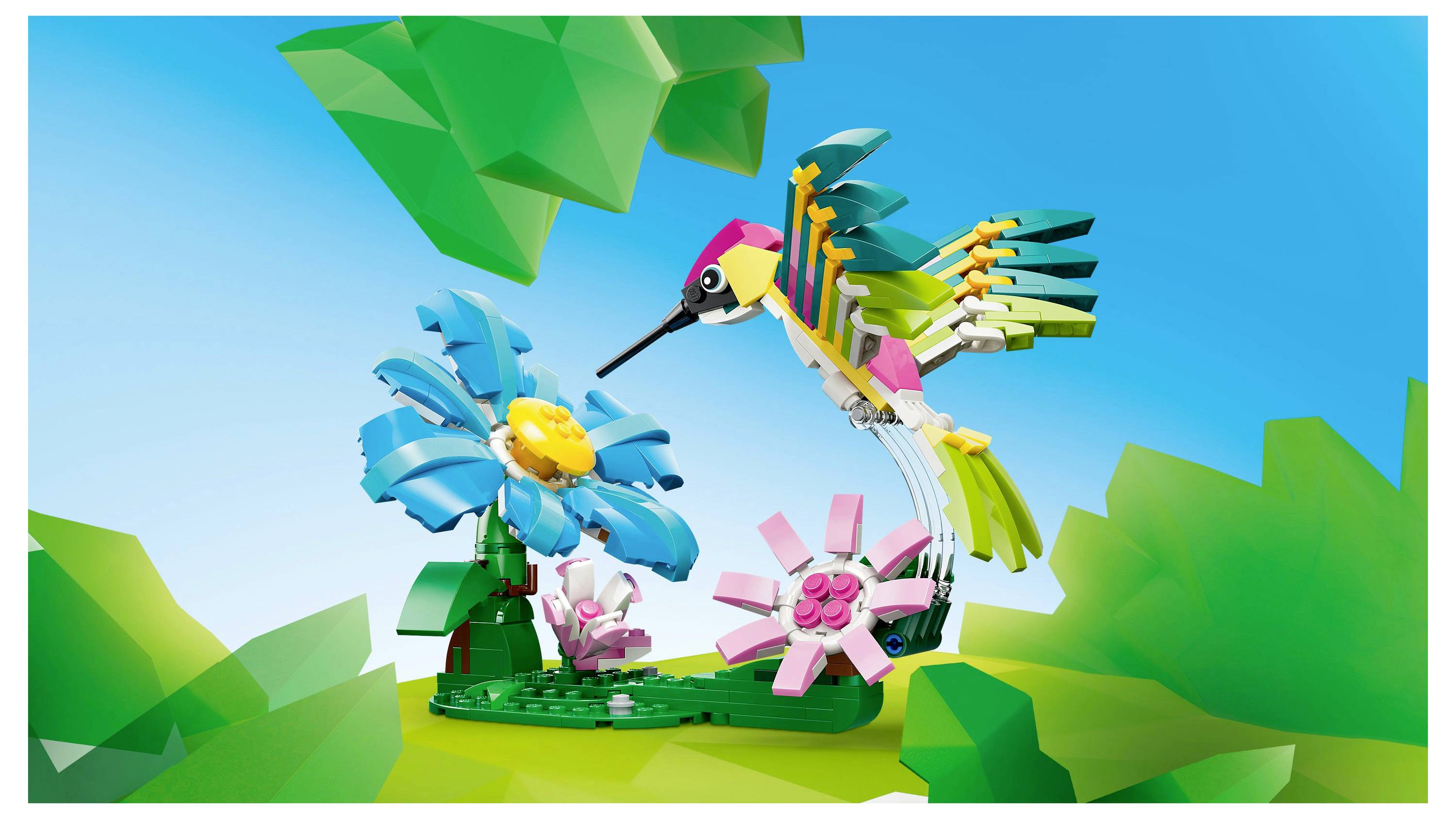 Barevný LEGO kolibřík se vznáší vedle modrých a růžových květin na zelené základně, s jasnou oblohou v pozadí.