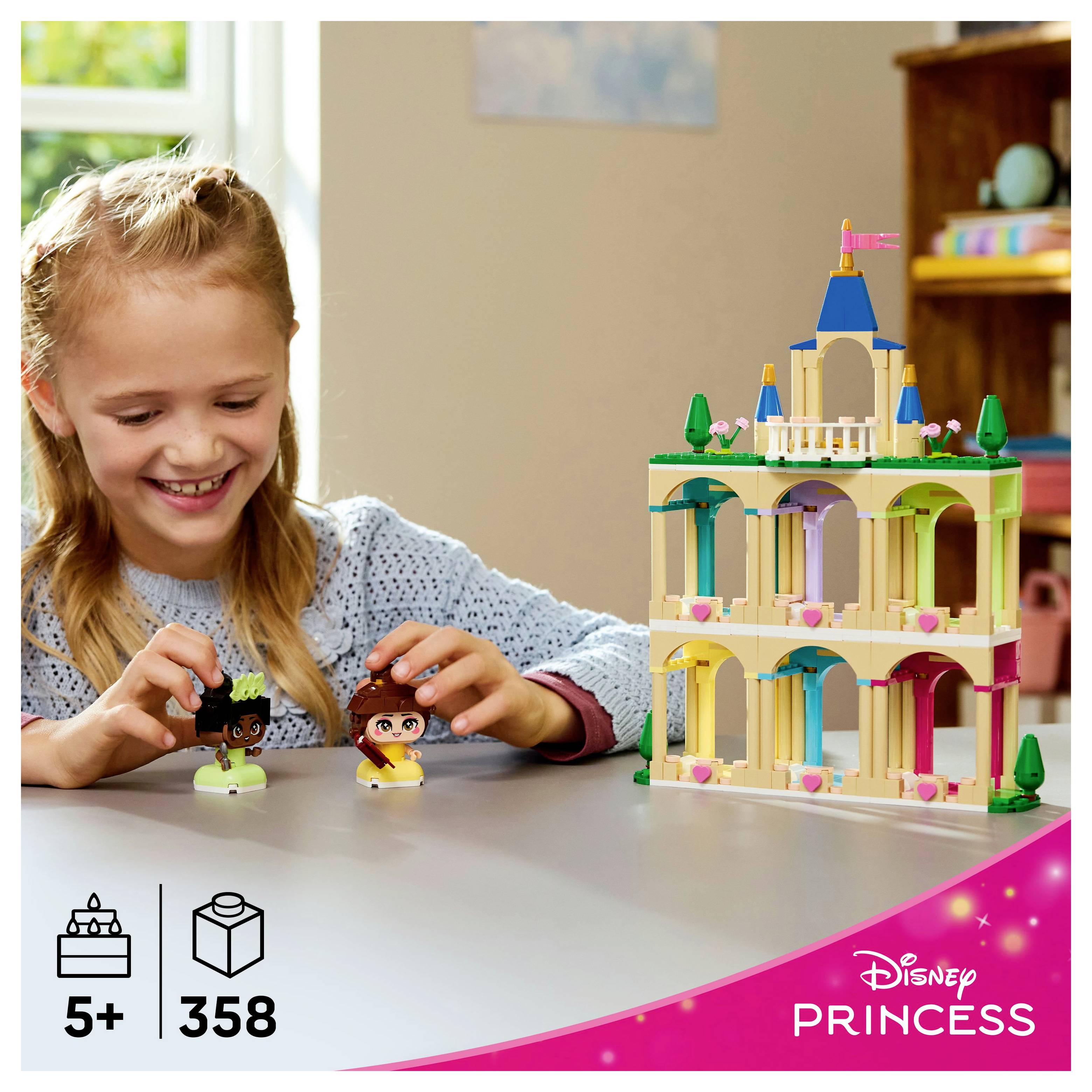 Dítě si hraje s miniaturními figurkami vedle barevné stavebnice zámku označené pro děti od 5 let, obsahující 358 dílků. Je viditelné branding Disney Princess.