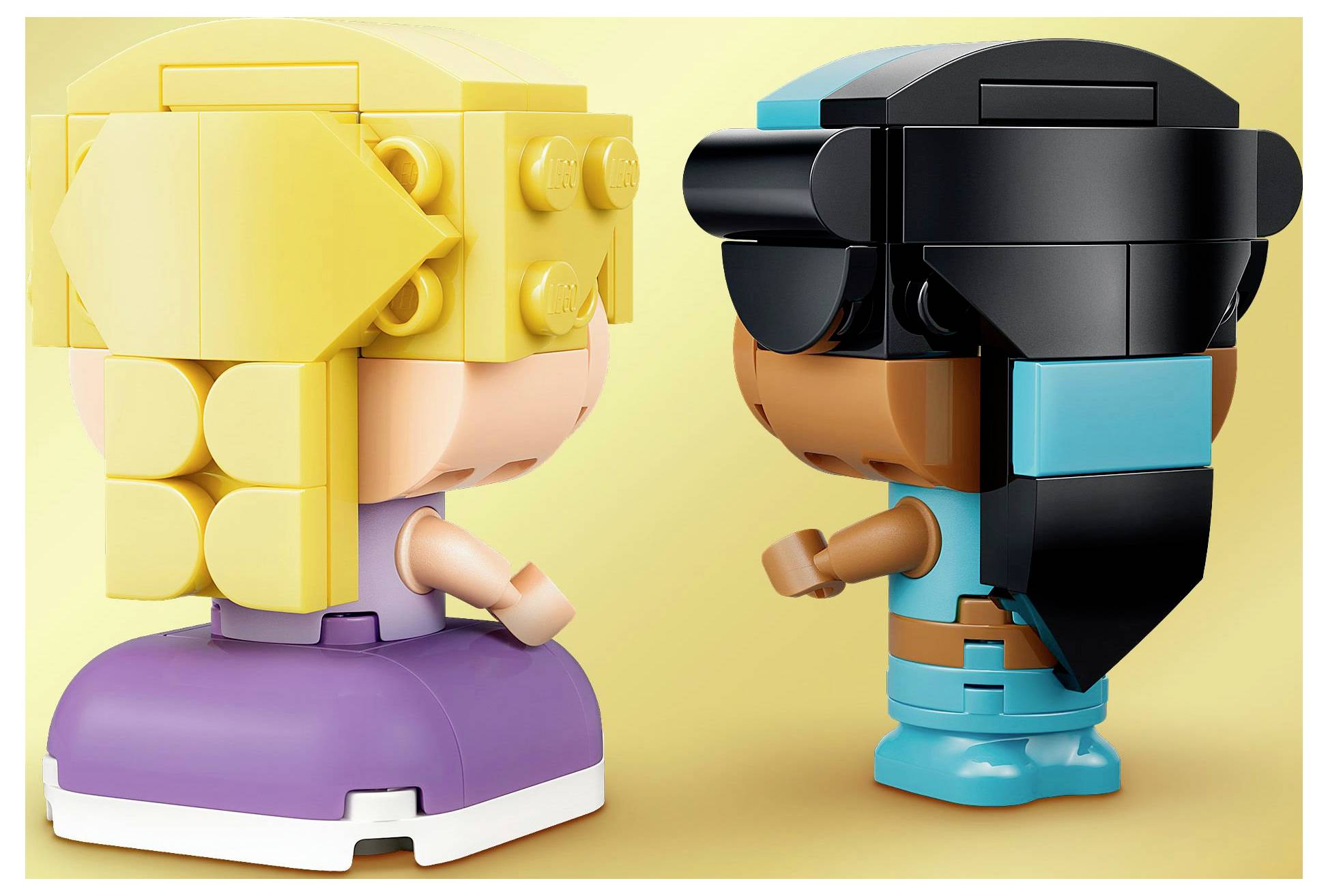 Dva hraví panáčci stojí proti sobě na žlutém pozadí. Figurka vlevo má žlutou hlavu a fialovou základnu. Figurka vpravo má modrou základnu a dlouhé černé vlasy.