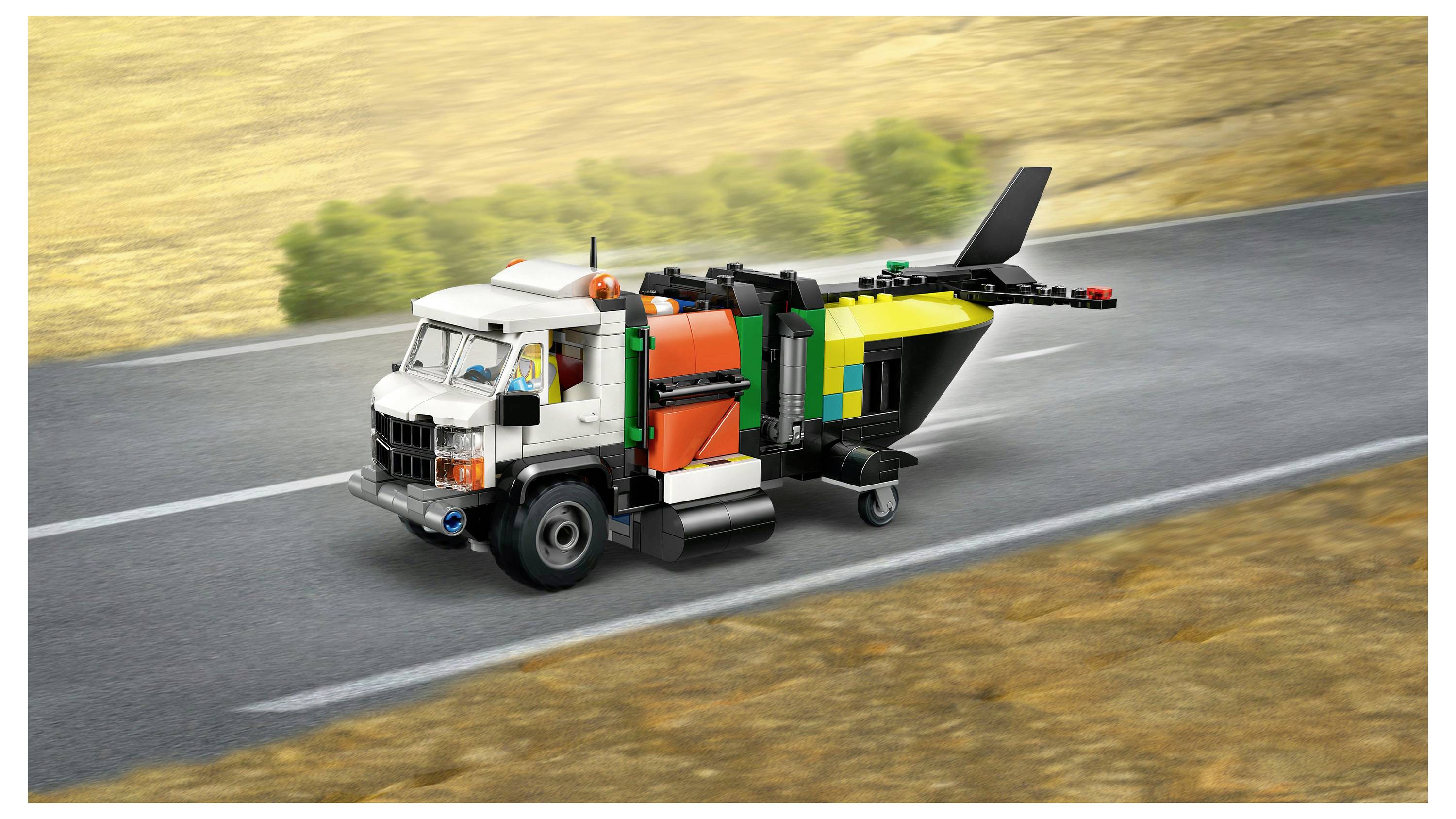 Popelářské vozidlo LEGO na silnici s barevným designem, které má bílou kabinu, oranžový a zelený kontejner na odpad a viditelnou zadní vyklápěcí část.