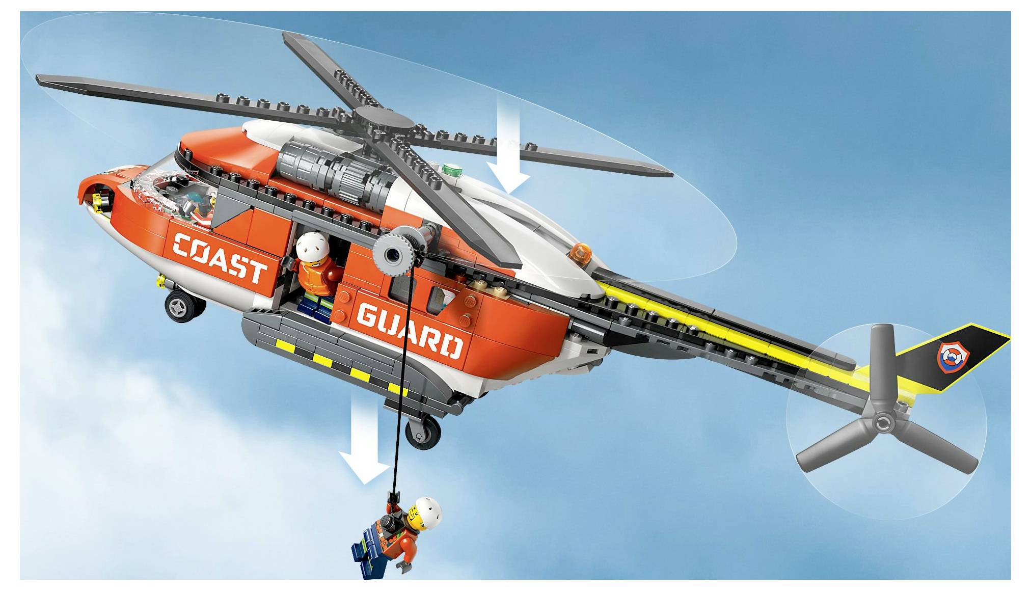 Hračkářská helikoptéra s nápisem „Pobřežní hlídka" na boku zvedá figurku v oranžovém obleku a s helmou pomocí navijáku před modrým nebem.