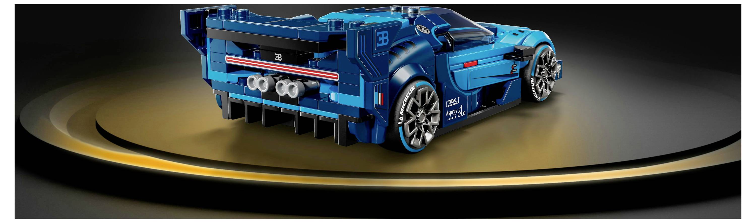 Detailní model modrého sportovního vozu s aerodynamickými prvky a výrazným zadním křídlem, zachycený na elegantním černozlatém povrchu.