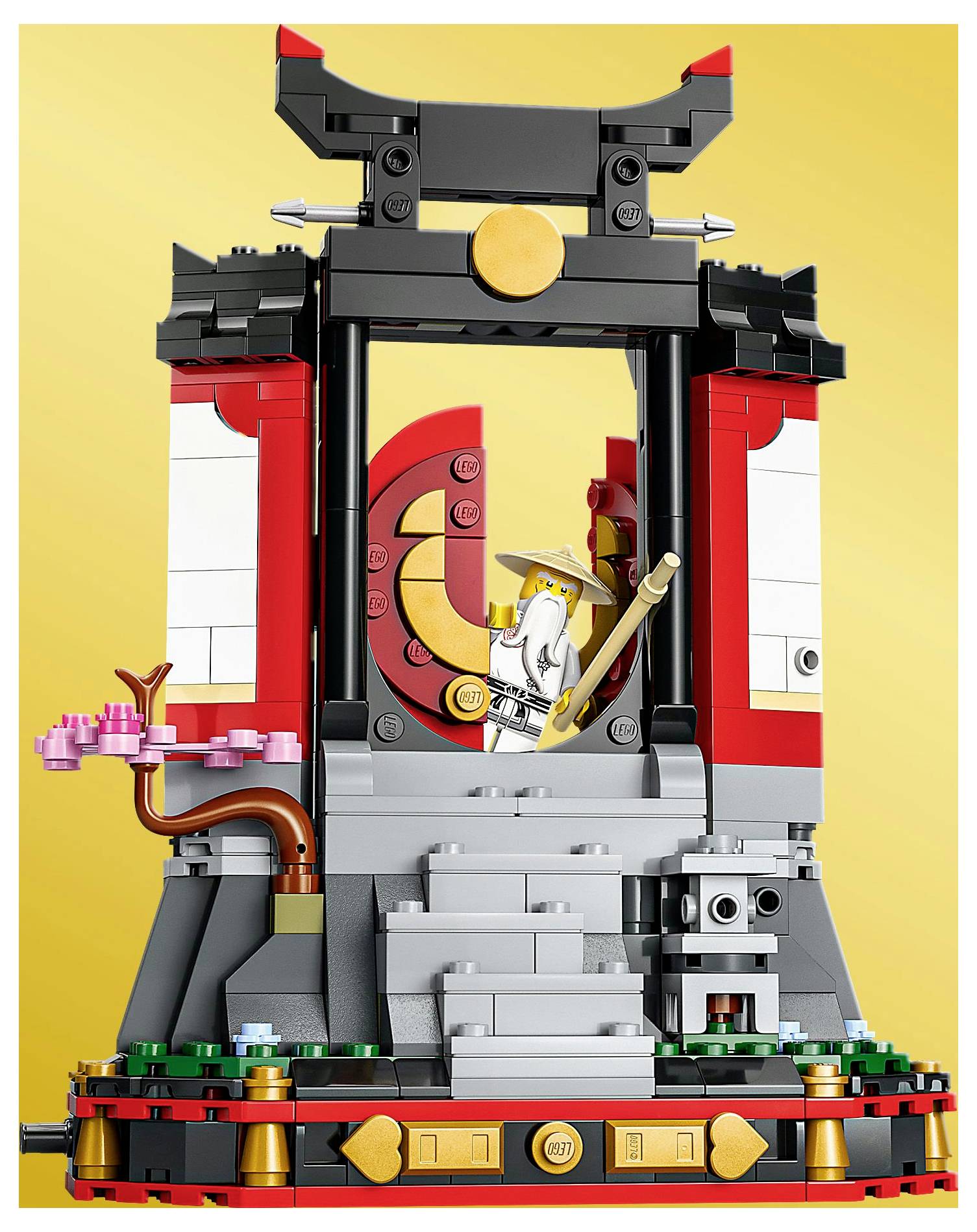 Sada LEGO s detailní svatyní s červenými a černými akcenty, třešňovým stromem a minifigurkou držící hůl uprostřed.