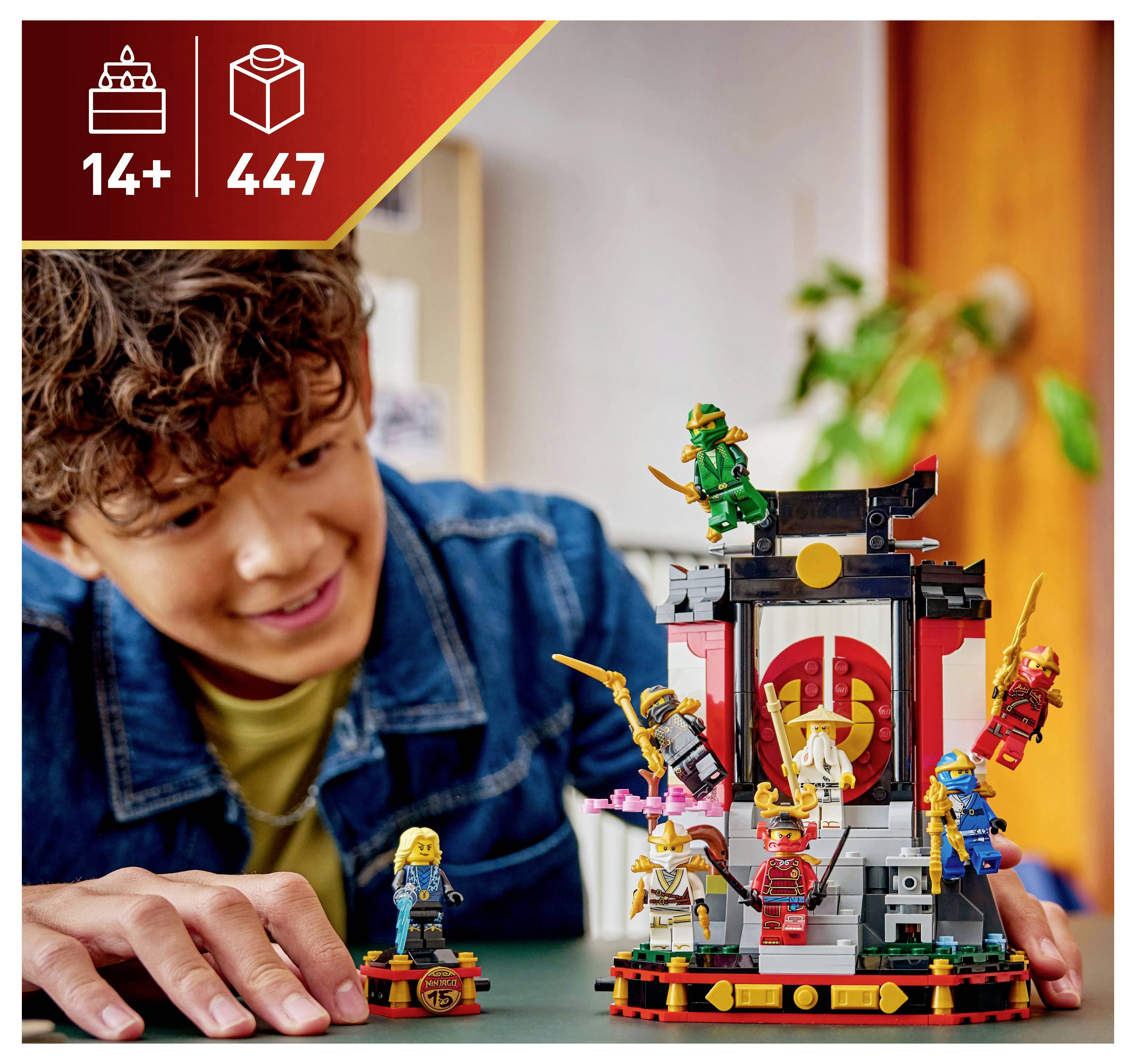 Osoba se usmívá, zatímco skládá složitou sadu LEGO složenou z několika miniaturních figurek a malé stavby, označenou '14+' a '447 dílků'.