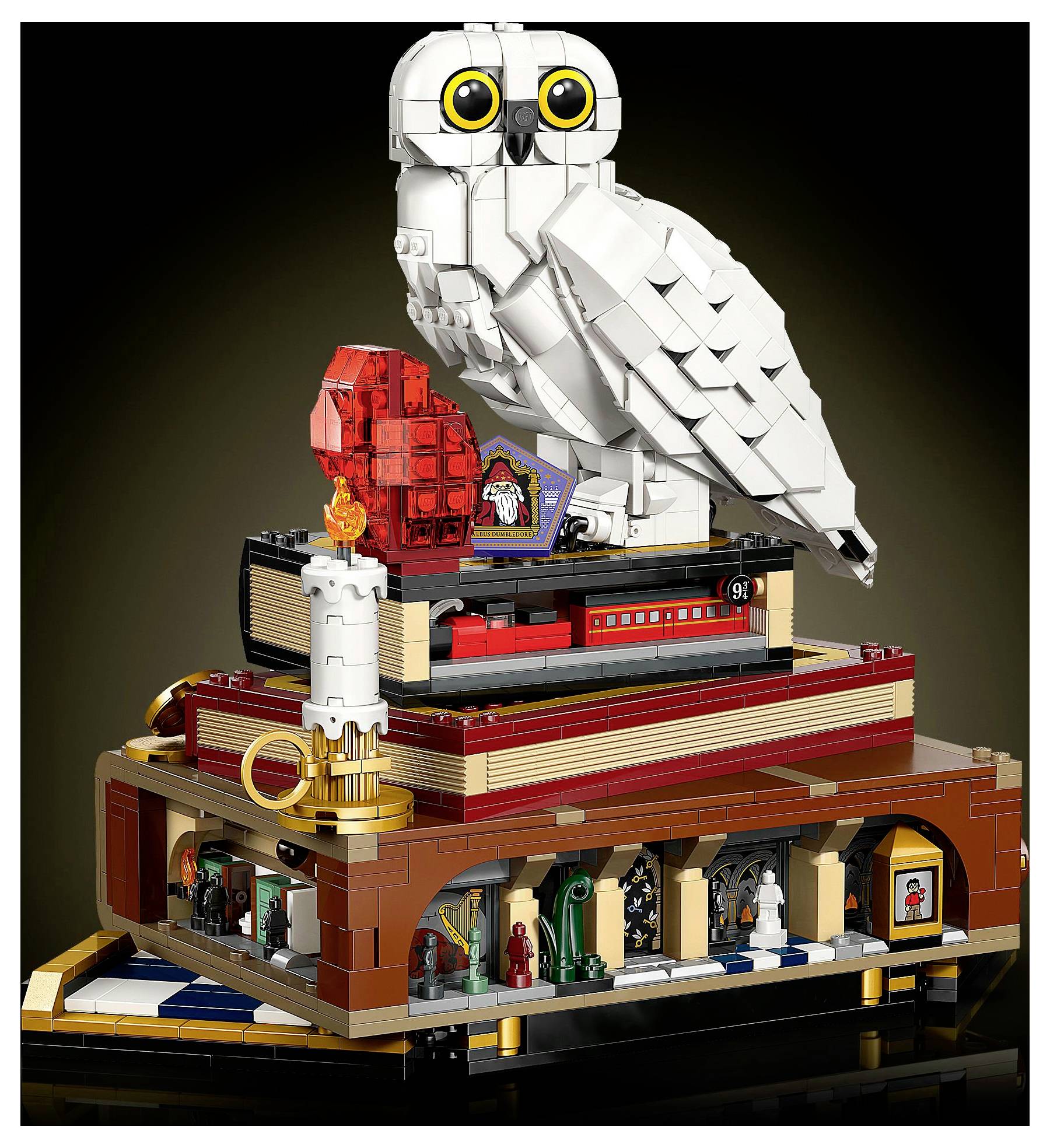 Model LEGO zobrazující velkou bílou sovu sedící na plošině. Dole je červený vlak s označením '9¾' a svíčka s detailem plamene.