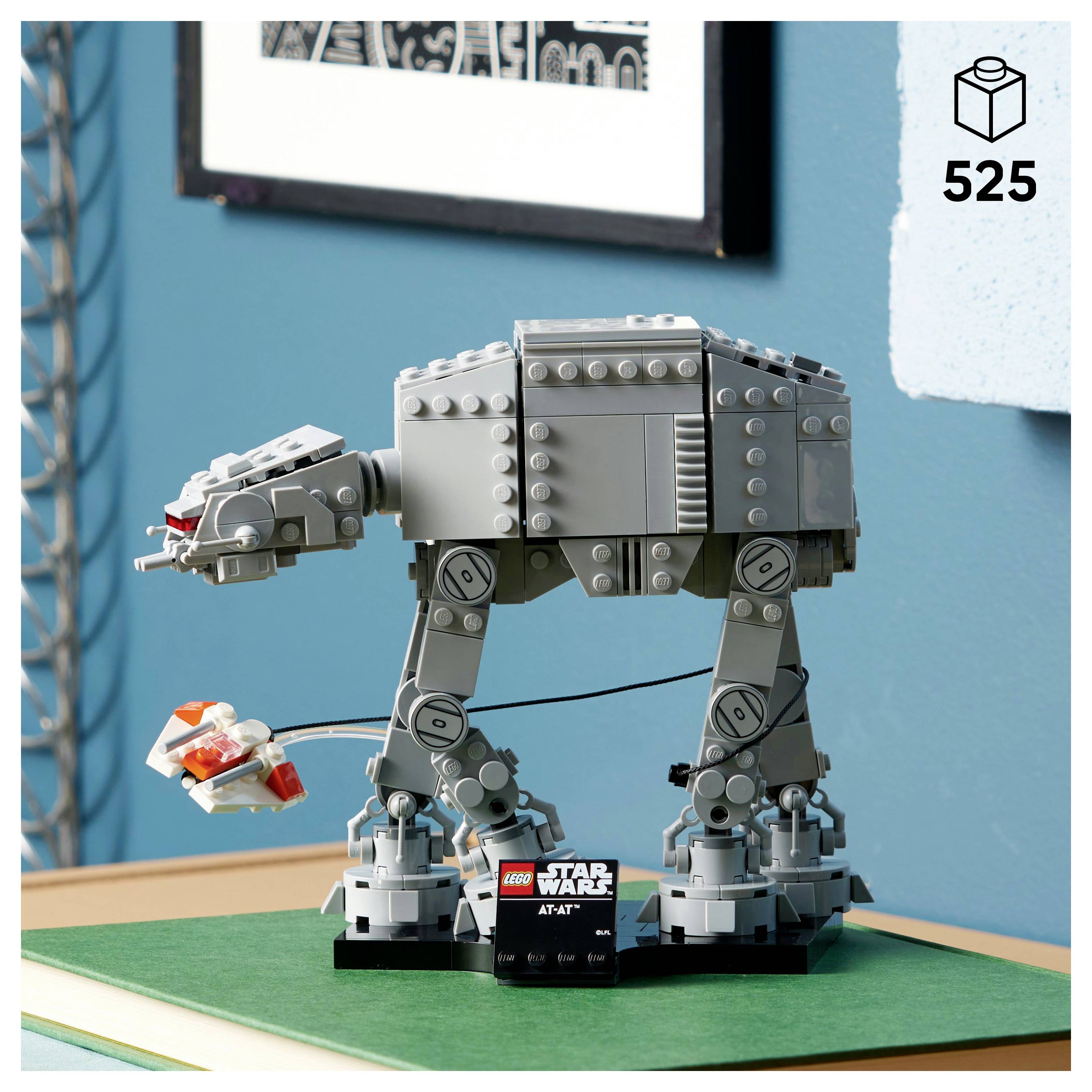 Model LEGO AT-AT z 'Star Wars' na zelené ploše, s menší LEGO figurkou vedle něj. Na krabici je uveden číslo sady 525.