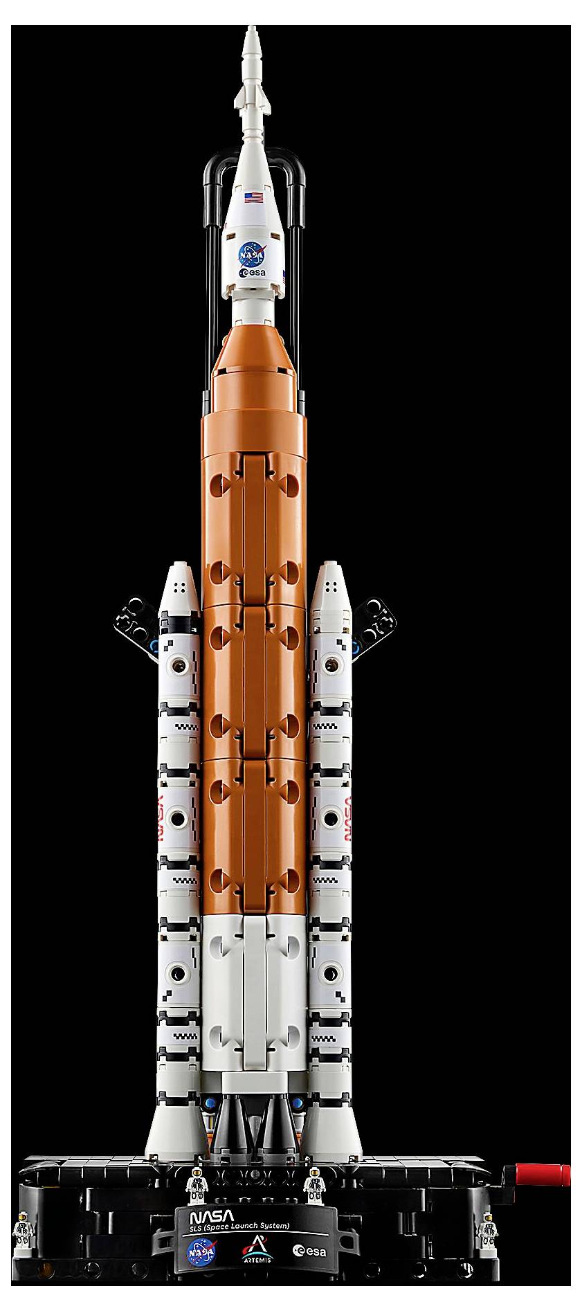 Model rakety NASA stojí svisle na výstavním podstavci, který je tvořen oranžovými a bílými segmenty, s detaily připomínajícími motory a přídavné raketové stupně.