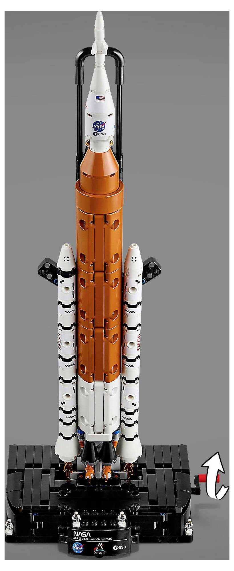 Detailní LEGO model rakety NASA, převážně v oranžové barvě s bílými boosters, umístěný na podstavci, který ukazuje realistické detaily.