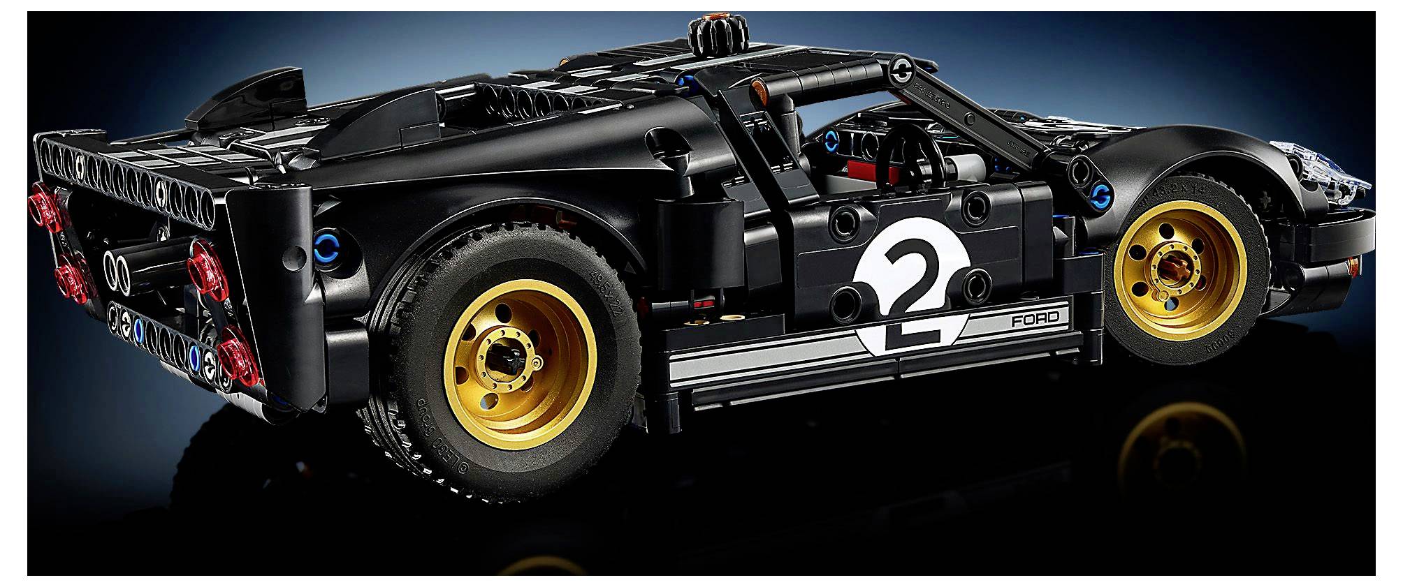Detailní černý model závodního auta LEGO s bočním číslem '2', zlatými koly a realistickými konstrukčními prvky, pohled z boku.