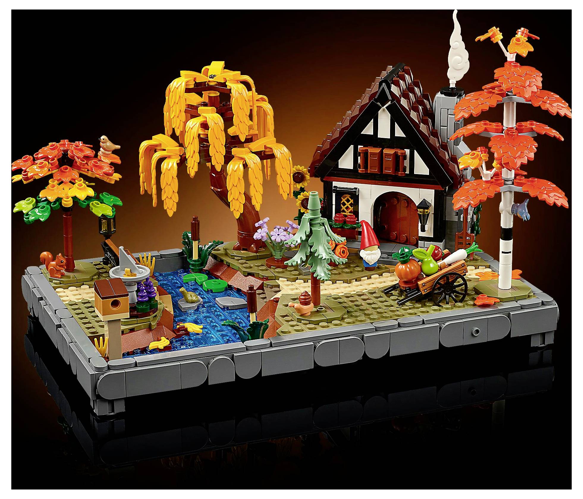 Podzimní scéna z kostek LEGO zachycující útulný dům, zářivě zbarvené stromy s oranžovými listy, rybník a vozík naplněný dýněmi, která navozuje atmosféru podzimu.