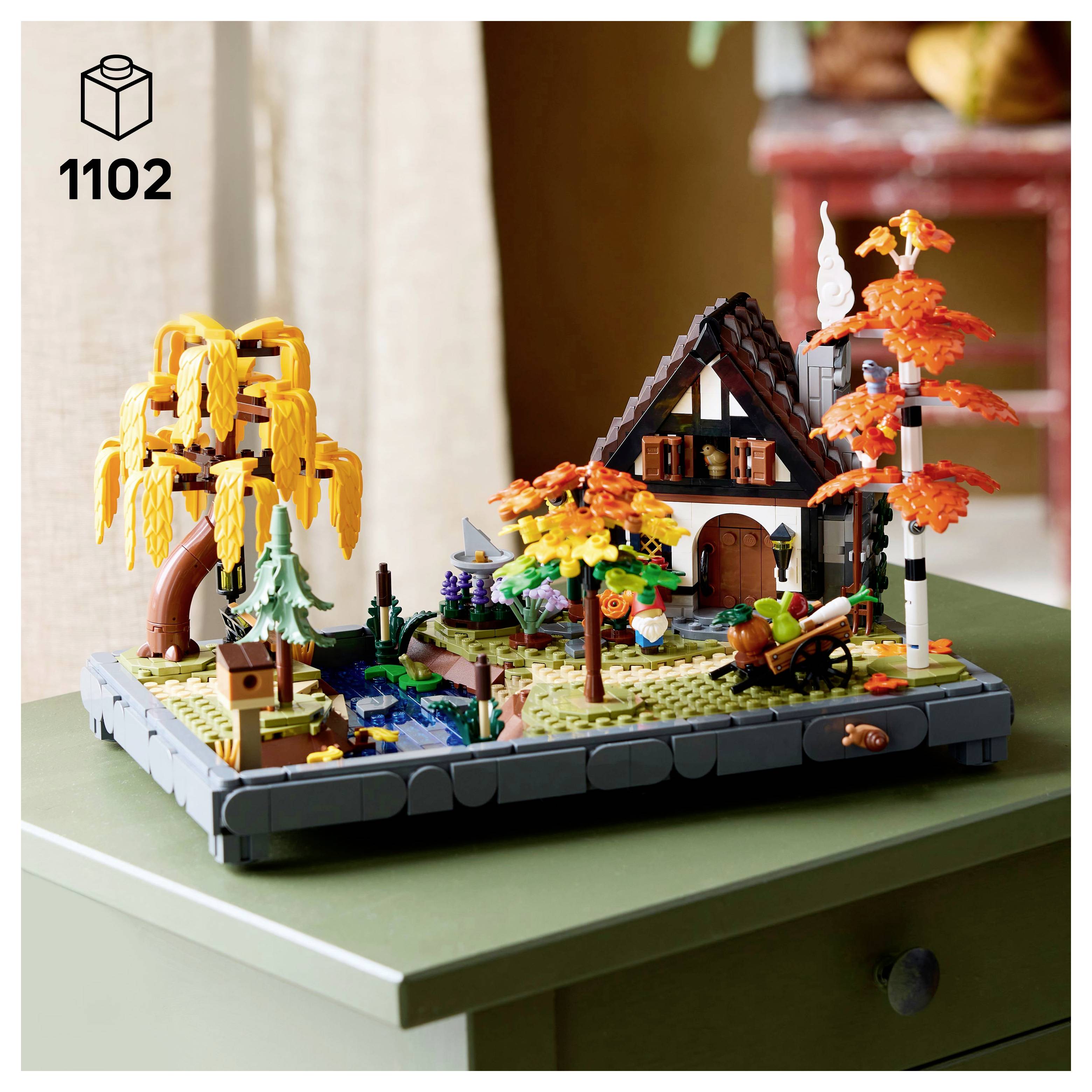 Detailní scéna LEGO setu zobrazující podzimní dům s oranžovými stromy, potokem a postavou na koni. Krabice je označena číslem '1102'.