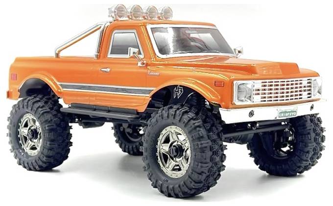 Oranžový hračkářský monster truck s velkými pneumatikami a chromovanými doplňky, otočený doleva, ukazující svůj robustní design a zvýšenou strukturu.