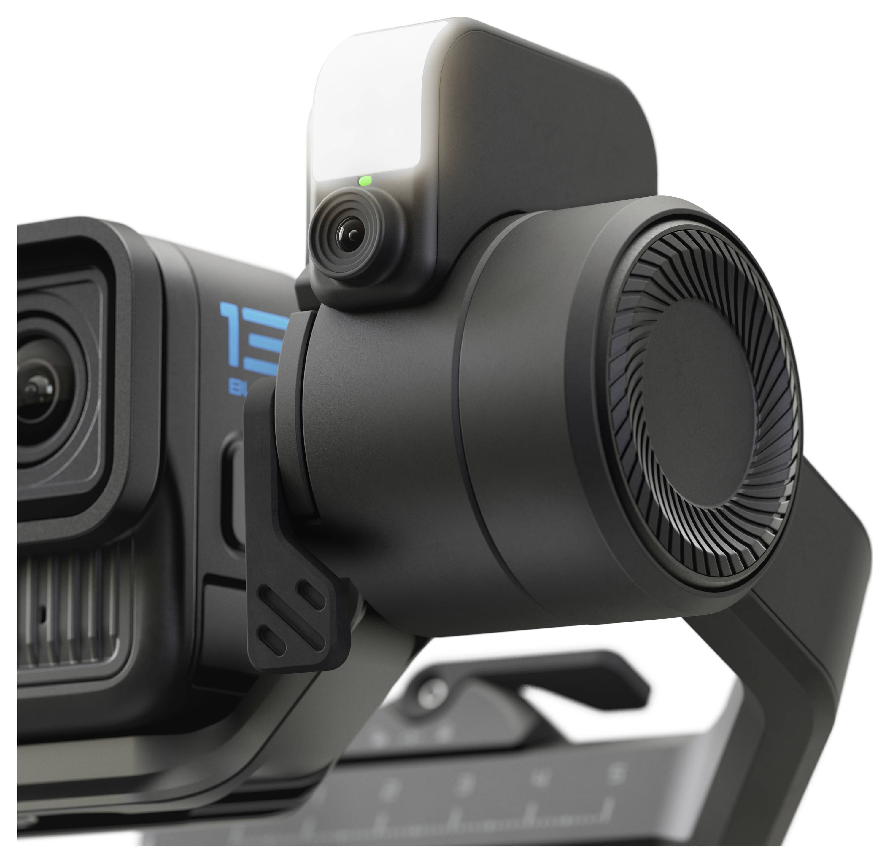 Detailní záběr černého stabilizátoru kamery s připevněným objektivem, svítícím indikátorem stavu a odvětrávaným designem, naznačující pokročilou technologii.