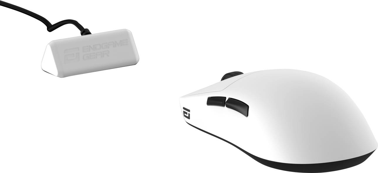 Bílá herní myš se dvěma postranními tlačítky a černým spodkem, značky 'ENDGAME GEAR'. Je připojena k obdélníkovému USB přijímači.