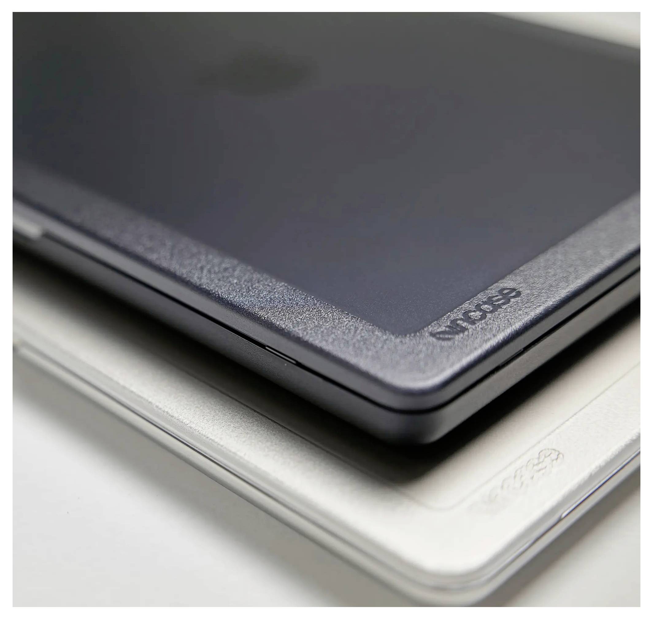 Detailní pohled na dva zavřené laptopy položené na sobě. Horní laptop je tmavě šedý a spodní stříbrný, oba s elegantním designem.