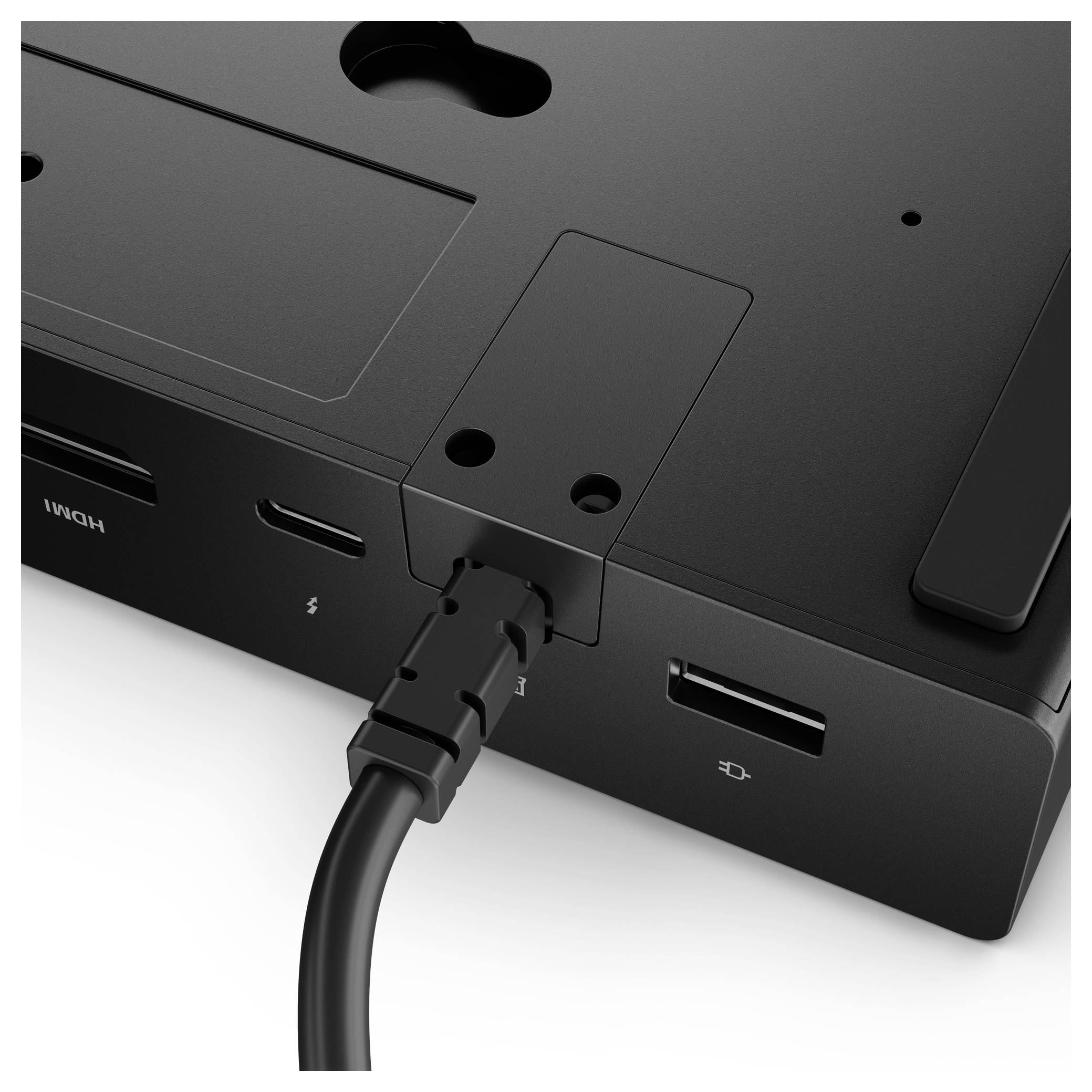 Detailní záběr černé dokovací stanice s několika porty, včetně HDMI, USB-C a USB. Kabel je připojen k jednomu z portů.