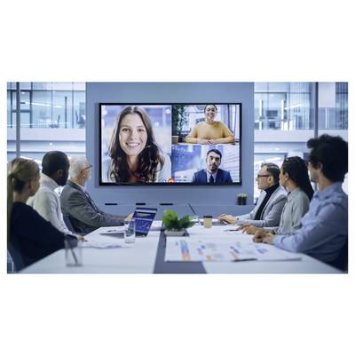 Lidé v zasedací místnosti se účastní videohovoru zobrazeného na velkém obrazovce, na kterém se objevují dvě ženy a jeden muž.