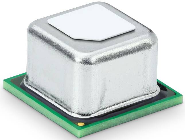 Kovová elektronická součástka se stříbrným pouzdrem leží na malé zelené desce plošných spojů.