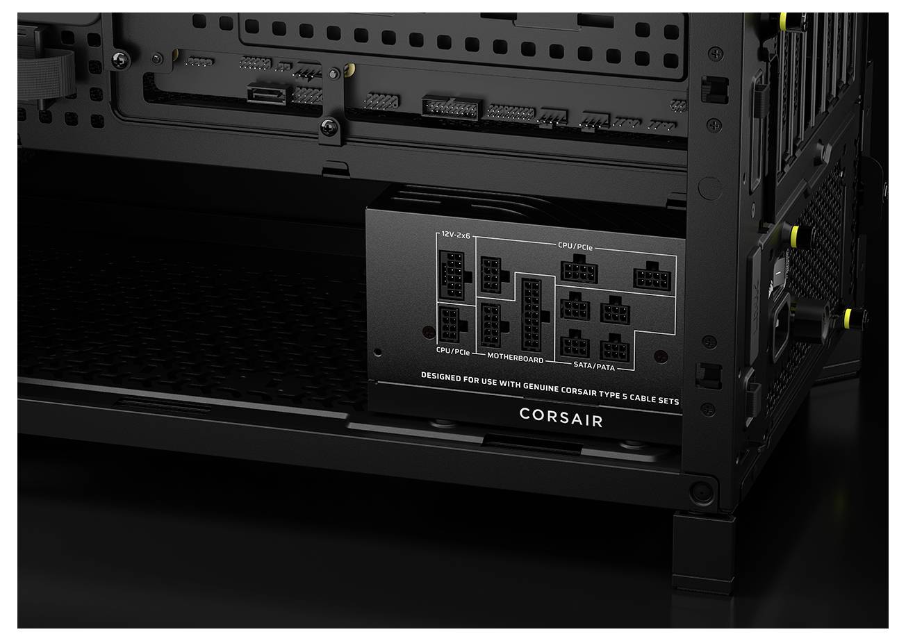 Černá napájecí jednotka Corsair nainstalovaná uvnitř počítačové skříně, zobrazující různé konektorové porty pro CPU, základní desku, SATA a periferní zařízení.