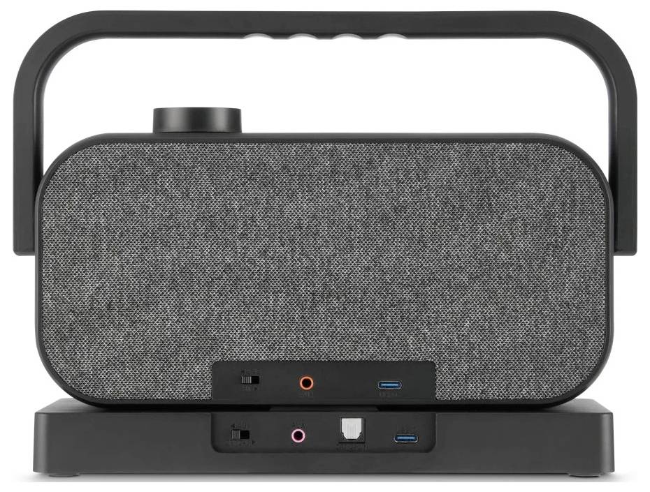 Reproduktor s čelní stranou potaženou látkou, s rukojetí nahoře, s porty pro USB a zvukové připojení u základny, umístěný na podstavci.