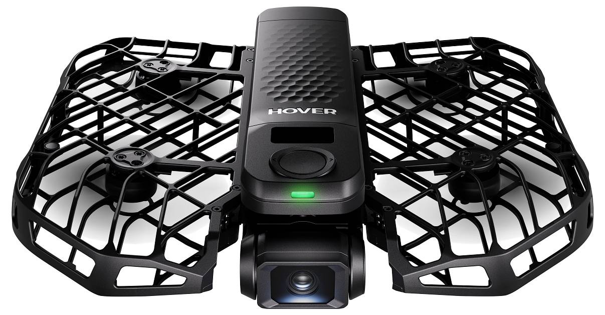 Kompaktní dron s ochrannou mříží kolem vrtulí, vybavený kamerou na přední straně a textem 'Hover' na horním povrchu.