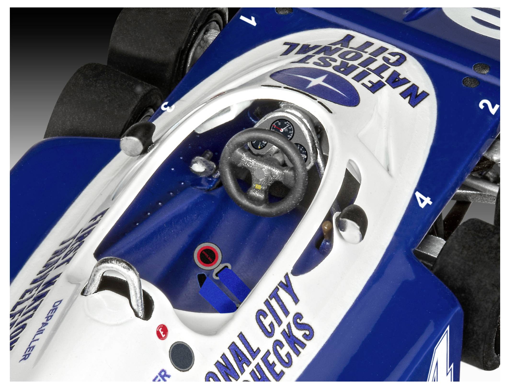 Detailní pohled do kokpitu modro-bílého vozu Formula 1, označeného štítkem 'First National City', zobrazující volant a ovládací prvky přístrojové desky.