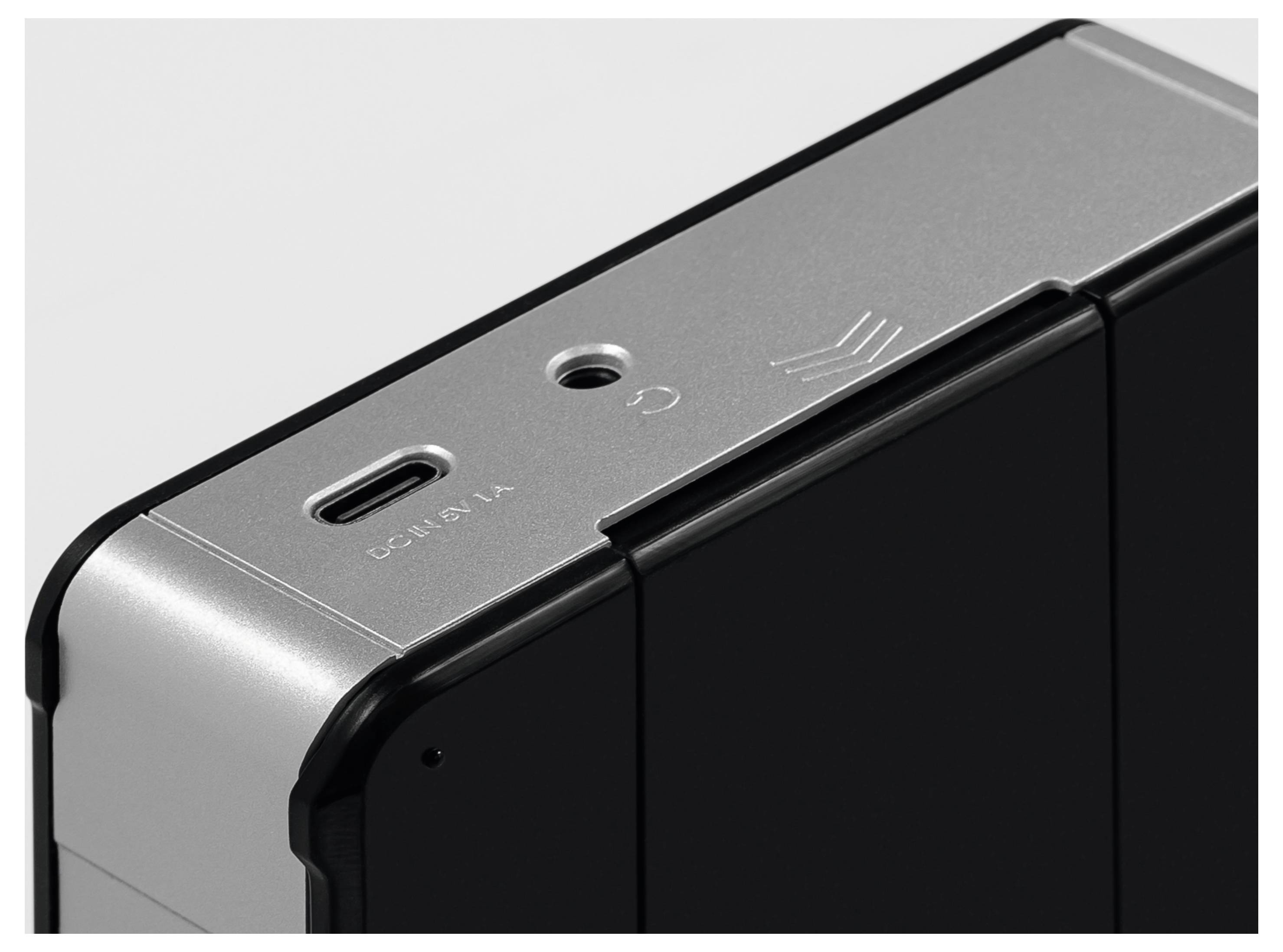 Detail zblízka zařízení zobrazující port USB-C a štítek 'DC IN 5V 1A', který uvádí vstupní specifikace na kovovém okrajovém panelu.