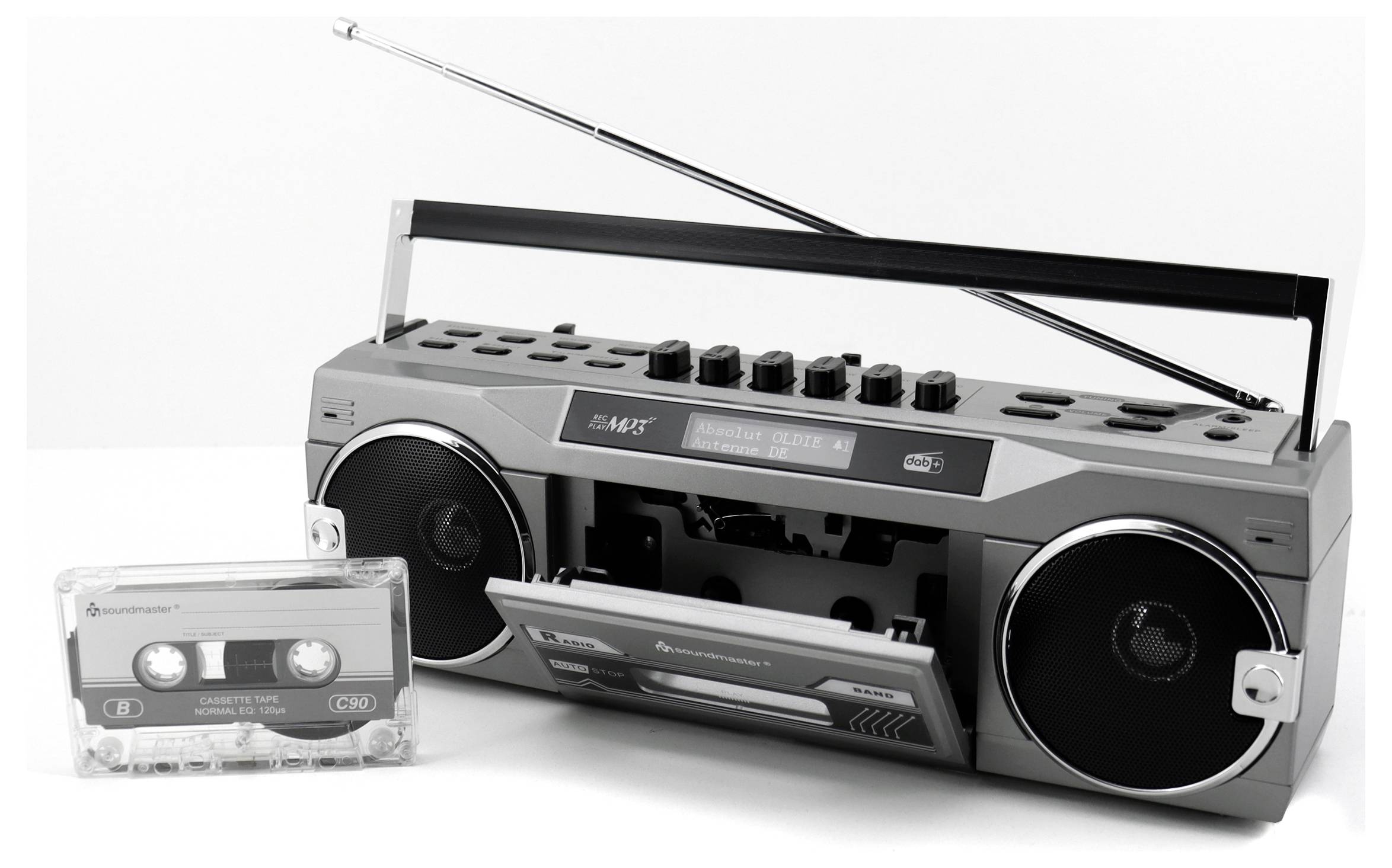 Retro boombox s vysunutou anténou stojí vedle kazety. Boombox má kulaté reproduktory a kazetový přehrávač.