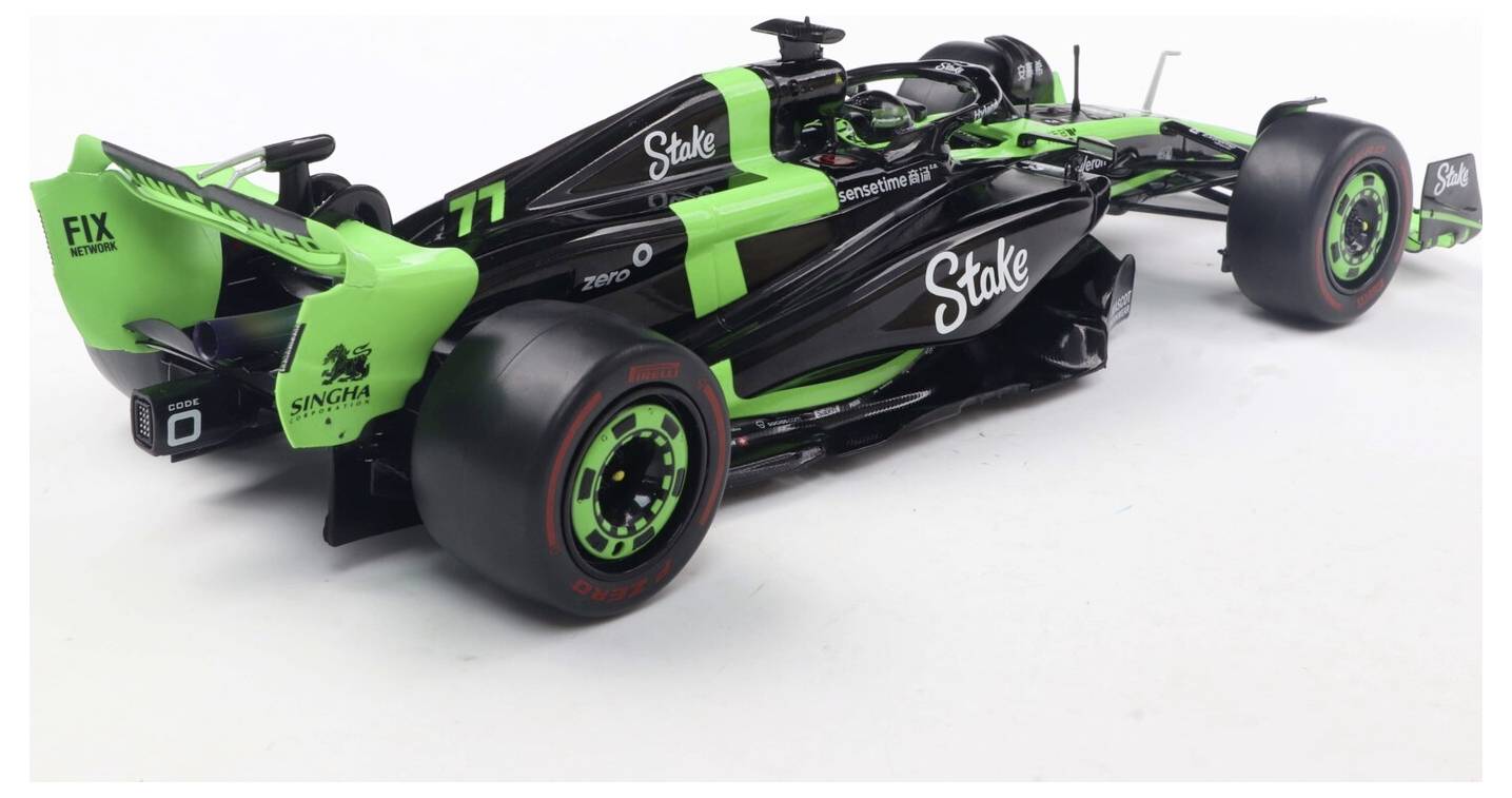 Černý a neonově zelený model formule 1 s viditelnými logotypy značky na karoserii a kolech, umístěný na jednoduchém pozadí.