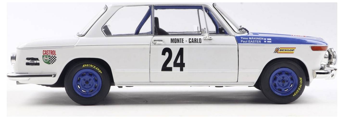 Model historického bílého závodního vozu s číslem '24' na boku, s modrými koly a sponzorskými nálepkami, připomínající vůz z rallye Monte Carlo.