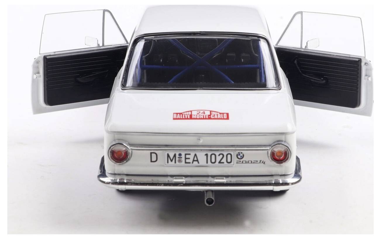 Bílý model auta je zobrazen zezadu s otevřenými dveřmi. Poznávací značka čte 'D MEEA 1020' a na zadním okně je nálepka 'Rallye Monte Carlo'.