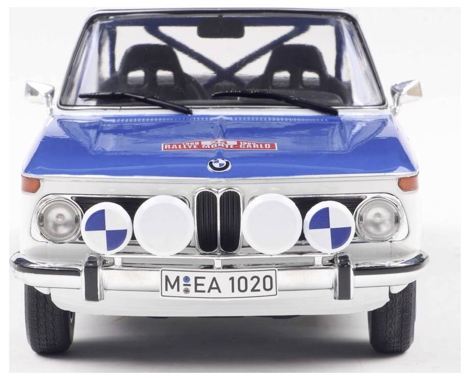Modrý klasický vůz se zavřenými kulatými světlomety a nálepkou rally Monte Carlo na kapotě je zobrazen zepředu.