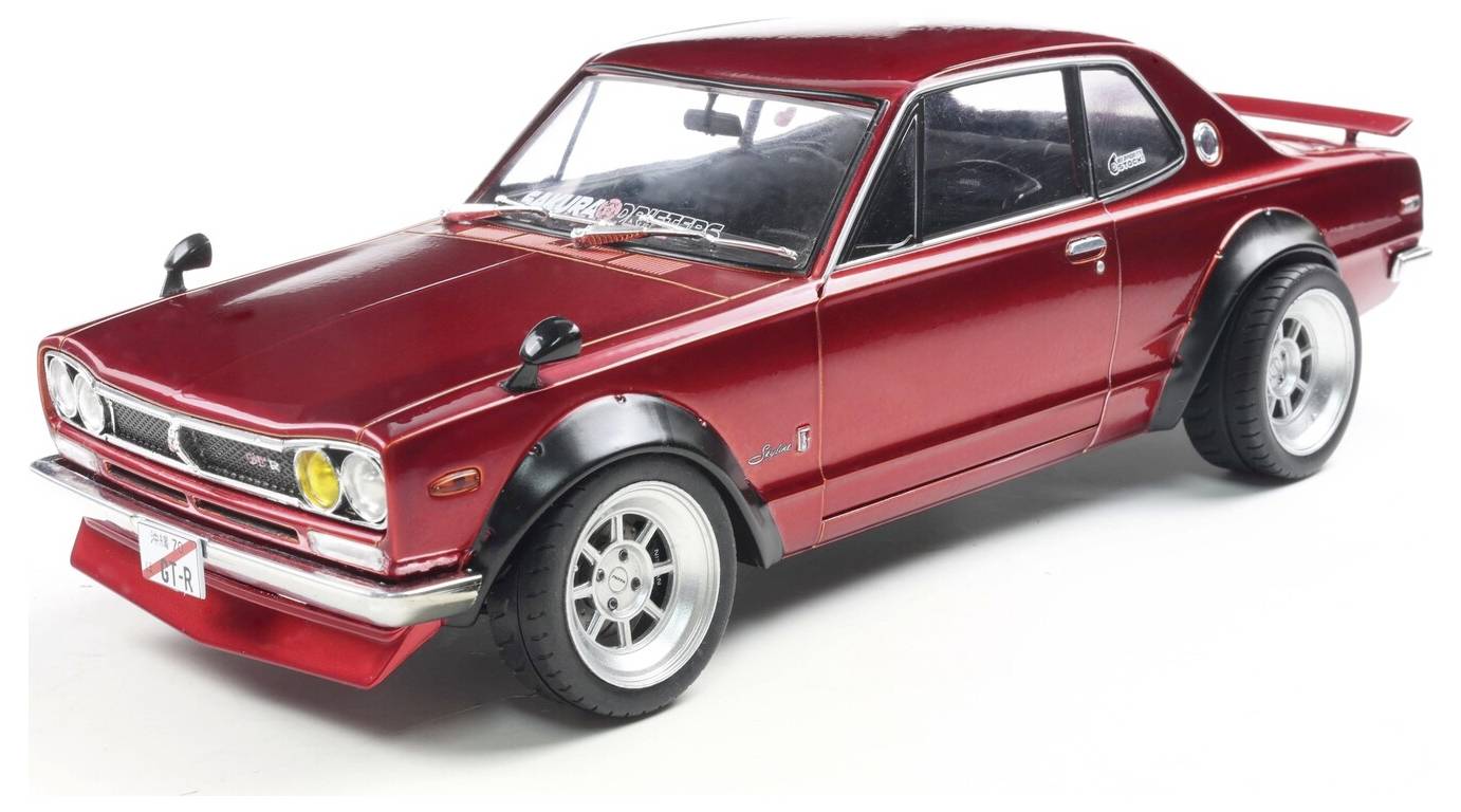 Leskle červený vintage model automobilu z bočního pohledu, zobrazující detailní designové prvky s černými nástavci blatníků a zadním křídlem.