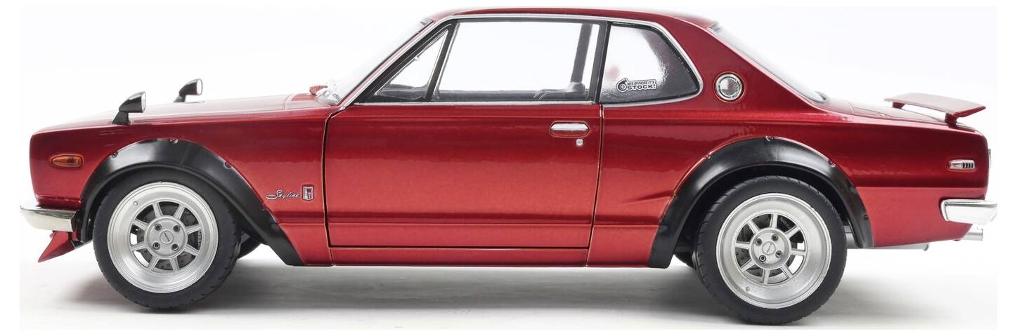 Červený vintage sportovní vůz s elegantním designem, rozšířenými blatníky a zadním křídlem, pohled z boku na bílém pozadí.
