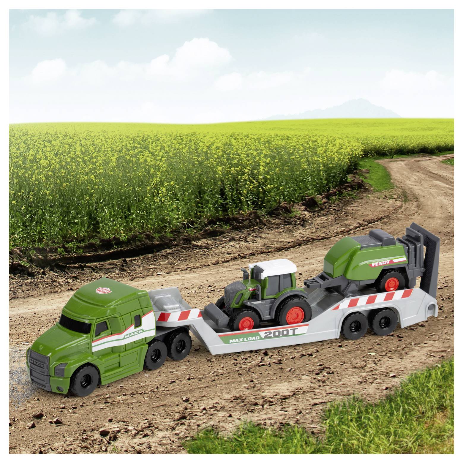 Zelený hračkářský traktor je naložen na plochém přívěsu, který je tažen zeleným nákladním vozem jedoucím po prašné cestě podél bujného pole.