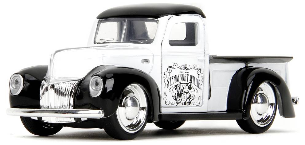 Bílý a černý vintage pickup truck s stylizovaným logem na dveřích, prezentující klasický design ze střední poloviny 20. století.