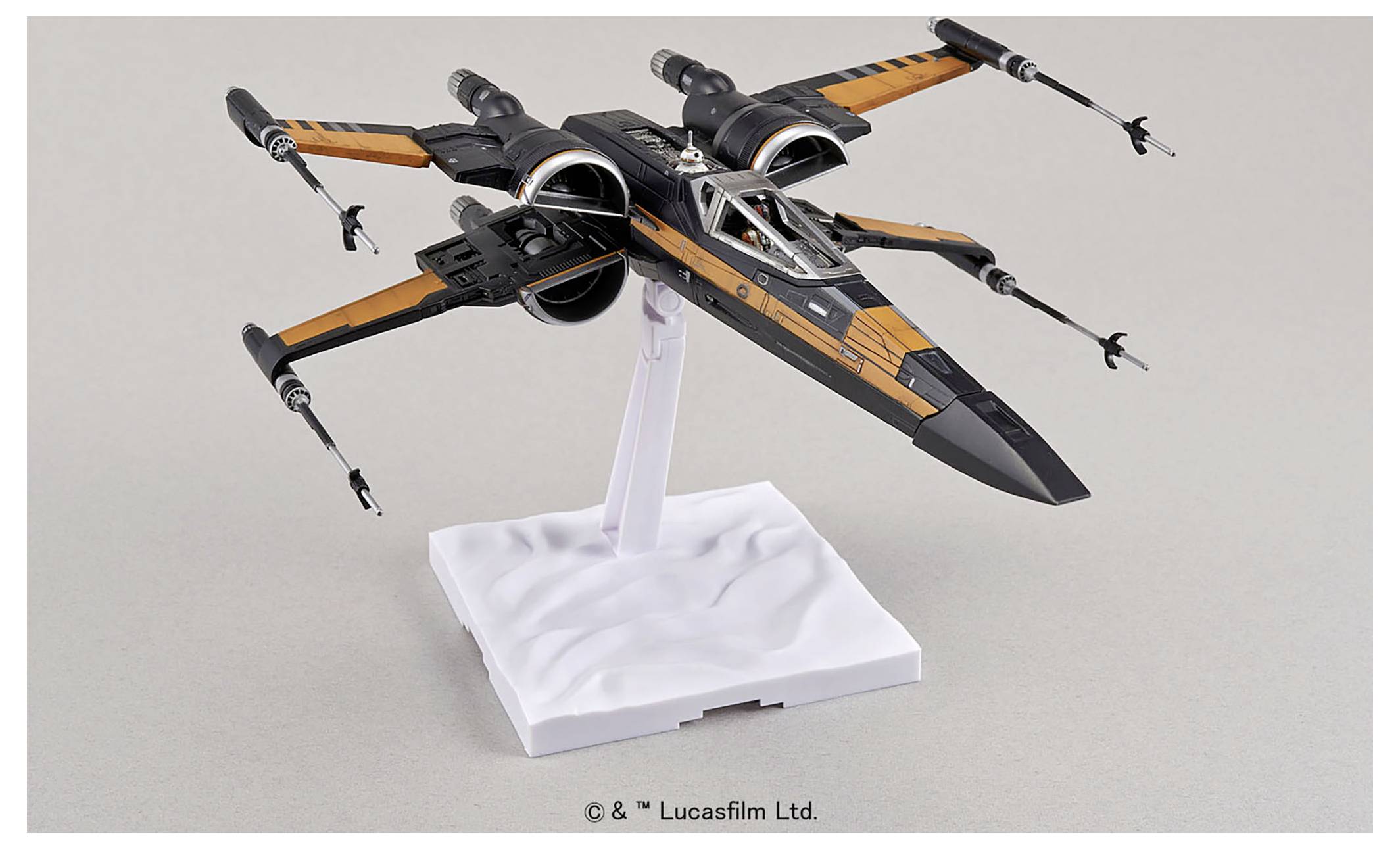 Model černobílé stíhačky X-wing z Star Wars, umístěný na bílém podstavci, se čtyřmi viditelnými laserovými kanóny.