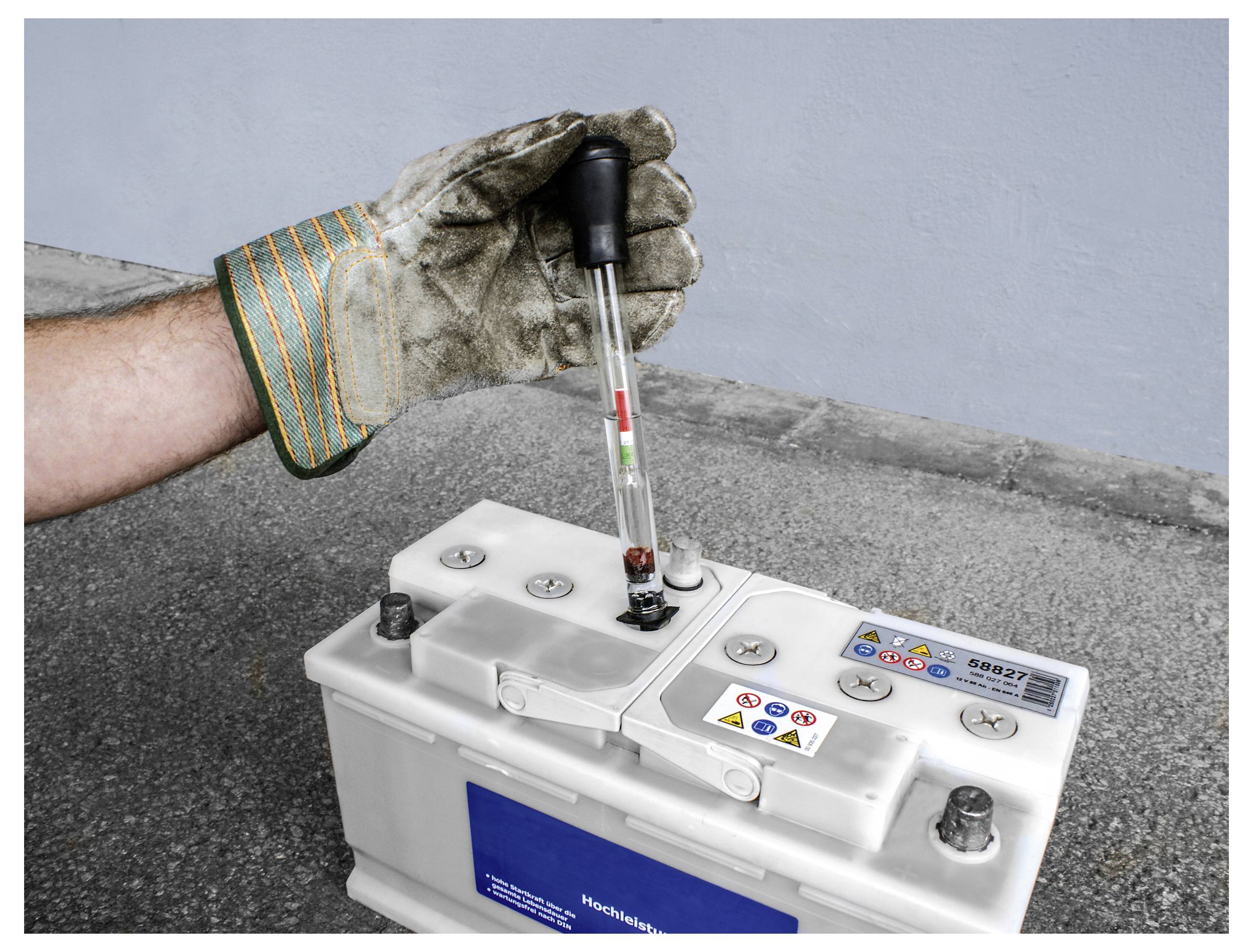 Rukavička rukou se testuje autobaterie hydrometry. Hydrometer ukazuje kapalinu indikující stav baterie.