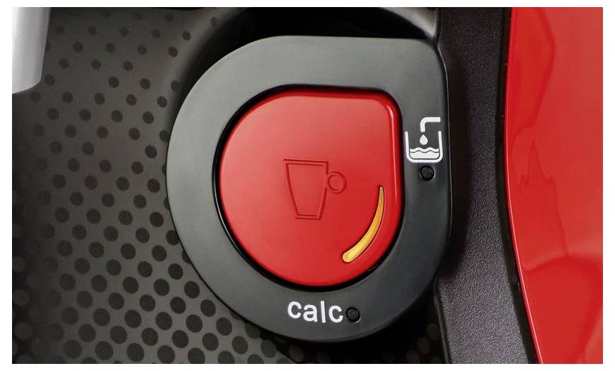 Červené kruhové tlačítko označené nápisem 'calc' na přístroji pro přípravu kávy, s ikonou šálku a páry, signalizující funkci odstraňování vodního kamene.