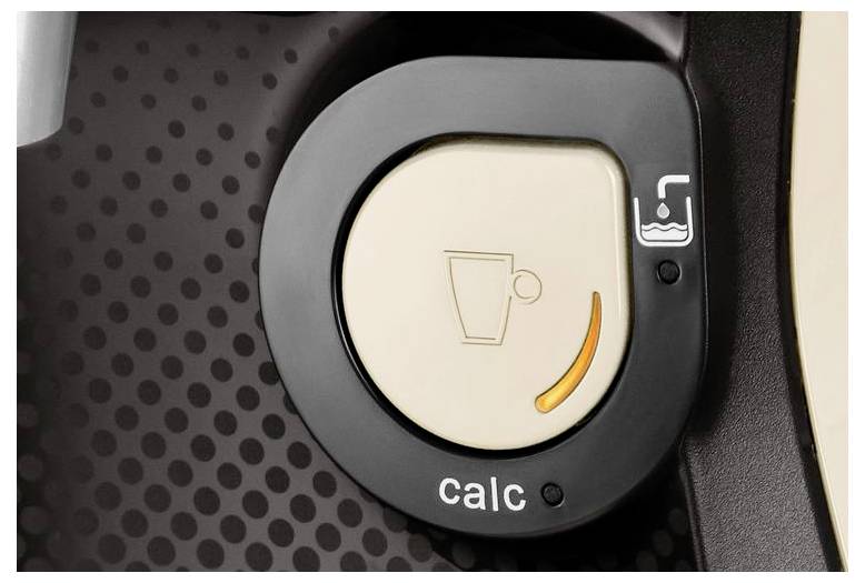 Detailní záběr indikátoru odstraňování vodního kamene na kávovaru, zobrazující ikonu šálku a slovo 'calc' s žlutým pruhem signalizujícím potřebu odškálování.