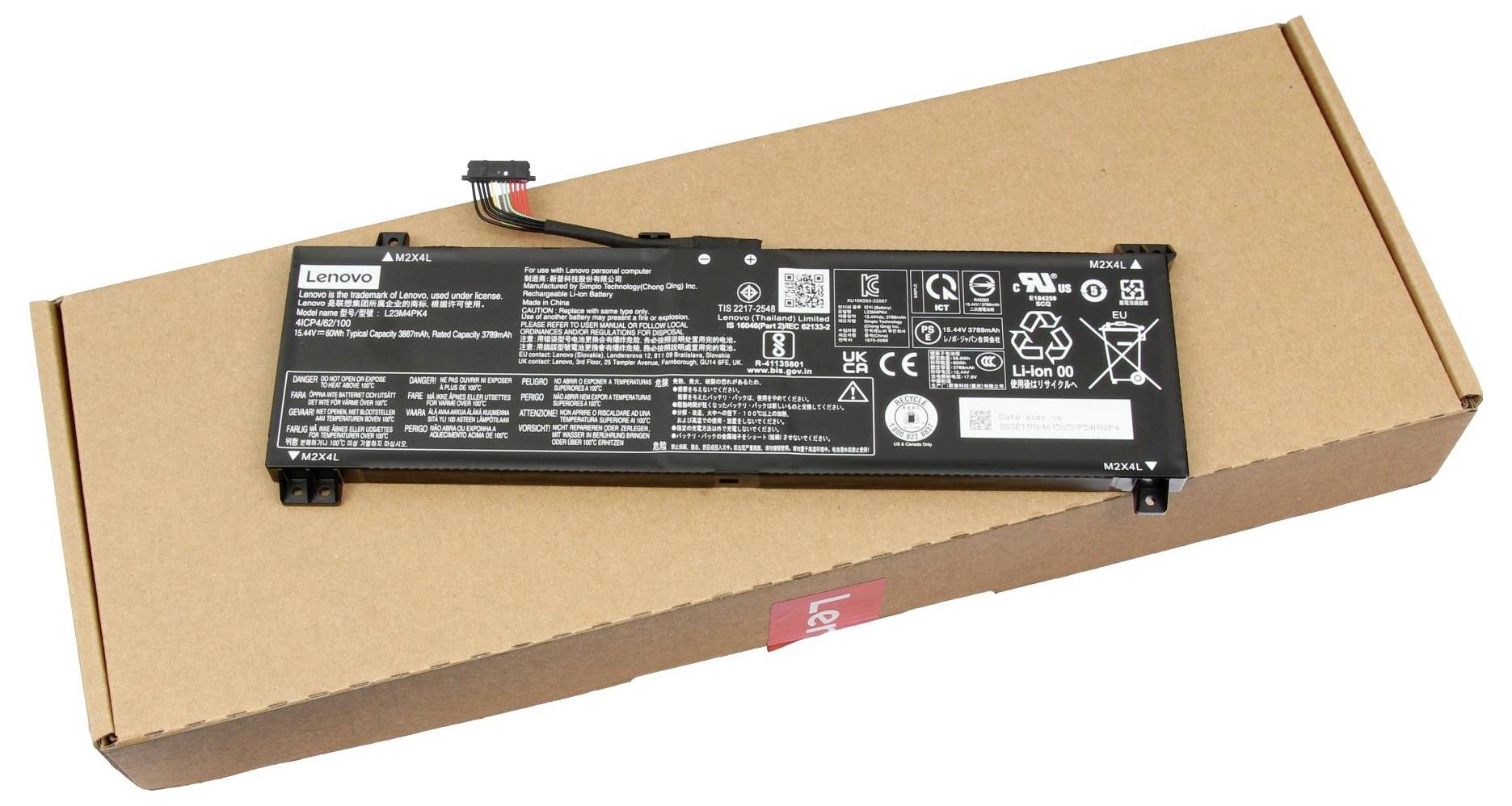 Obdélníková baterie pro notebook s detailním bílým textem na povrchu, umístěná na uzavřené hnědé krabici z lepenky, pravděpodobně od obalu.