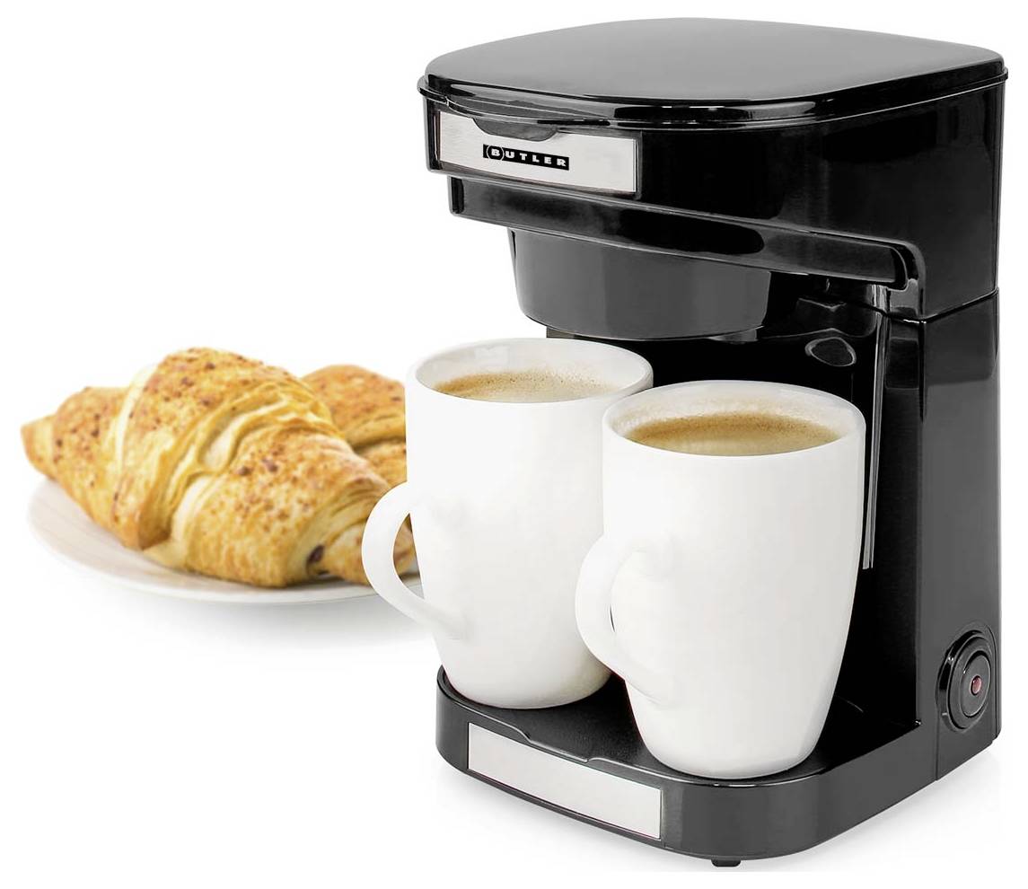 Černý kávovar se dvěma bílými hrnky naplněnými kávou, vedle talíře se dvěma croissanty.