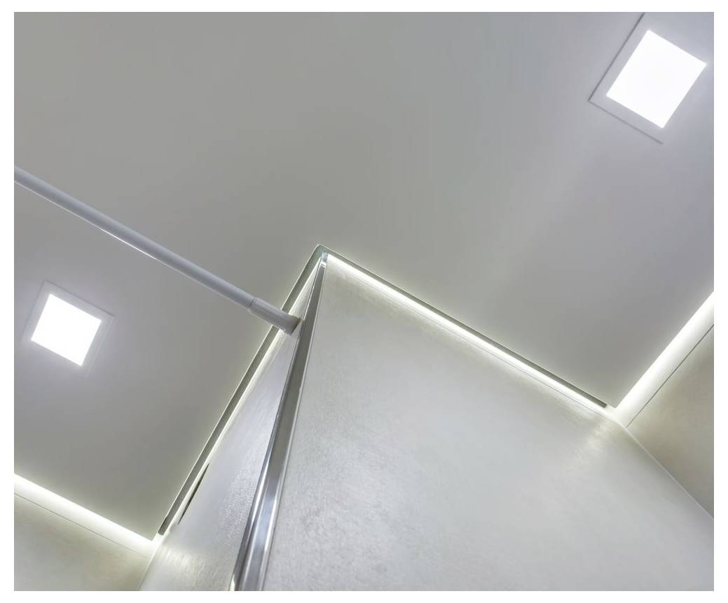 Pohled na moderní strop se zapuštěným osvětlením a elegantními liniemi, zdůrazňující minimalistický design.