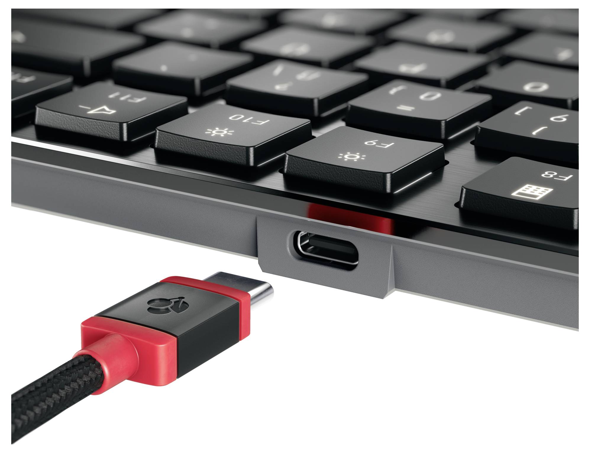 Kabel USB-C vedle klávesnice, znázorňující port USB-C připravený k připojení, zdůrazňující funkce konektivity a kompatibility.