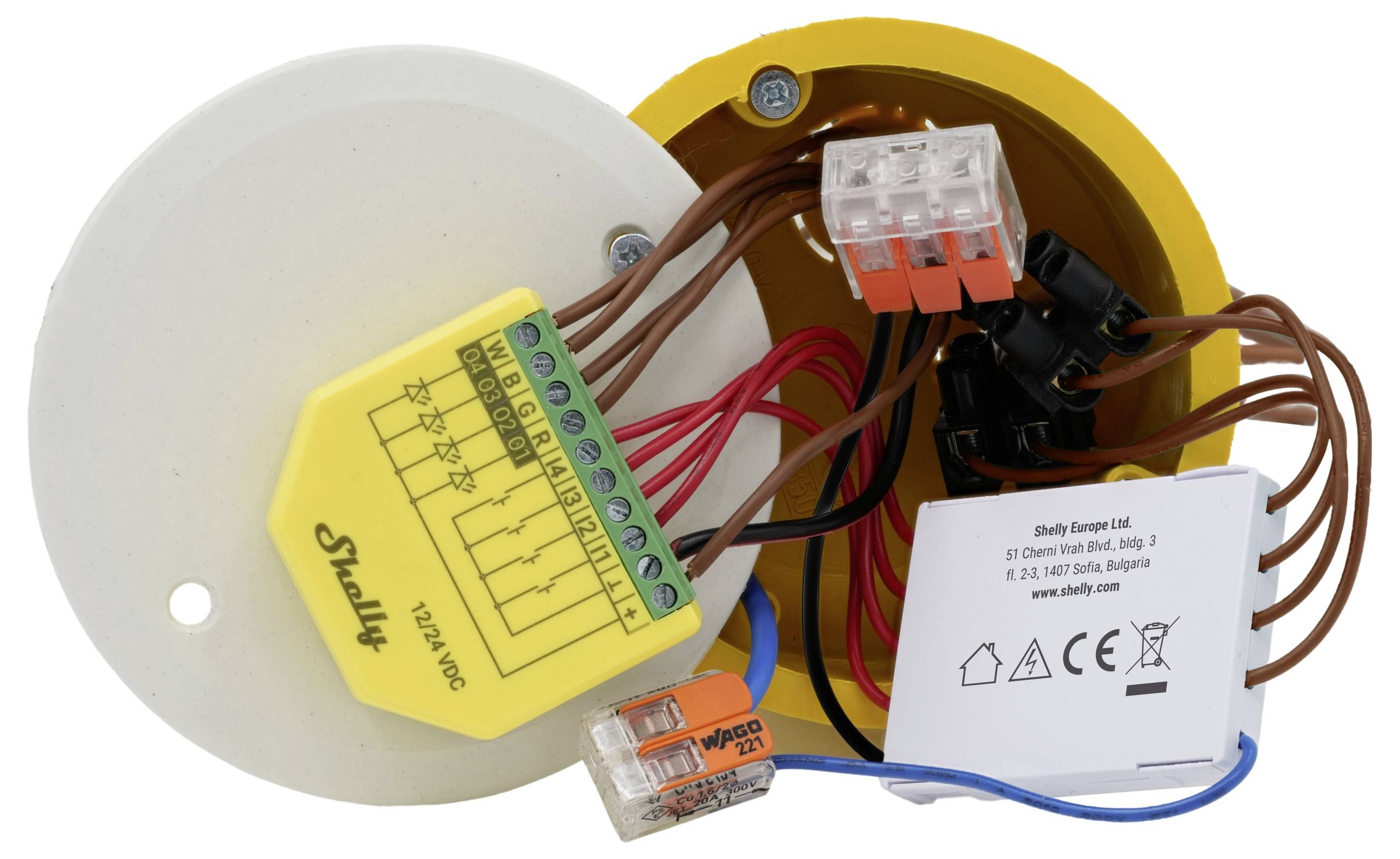 'Elektrické obvody a komponenty včetně zařízení Shelly, blokových konektorů a kabeláže v žluté kruhové skříni.'