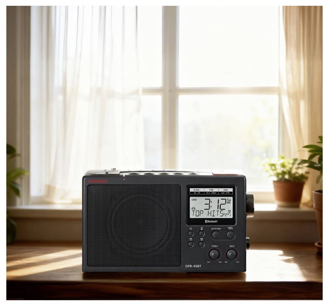 Na parapetu okna sedí vintage rádio vedle květináčů s pokojovými rostlinami, na displeji jsou zobrazeny údaje "3:12 PM" a "TOP HITS." Slunečním svitem proniká světlo oknem.