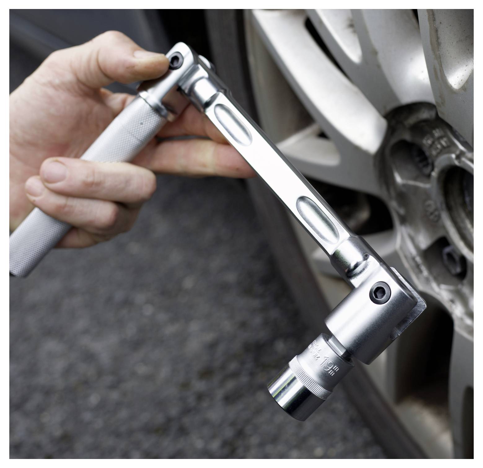 Ruka používající momentový klíč k utažení matice kola na automobilovém kole, což demonstruje správné používání nářadí pro údržbu vozidla.