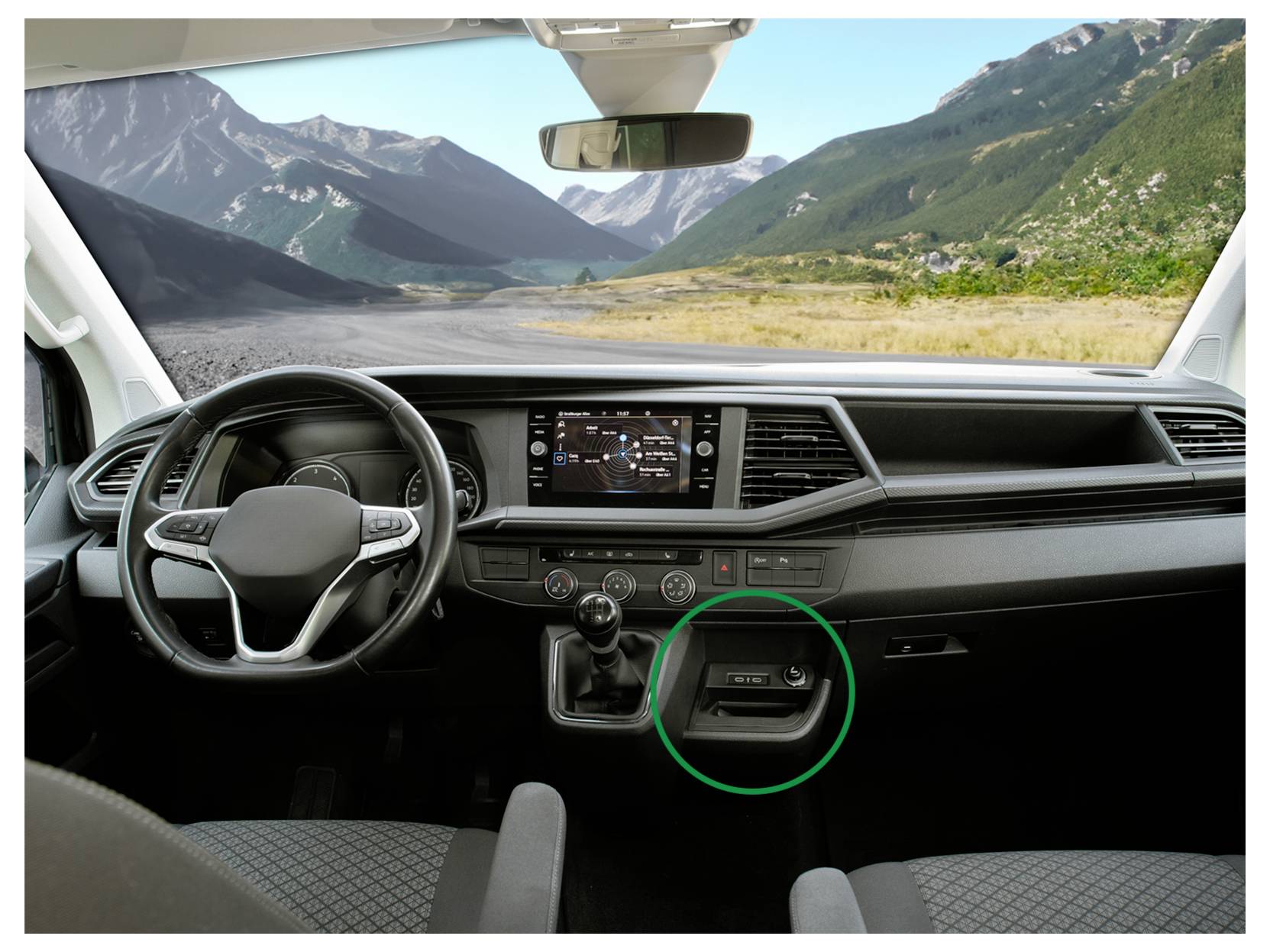 Interiér automobilu pohled ze předních sedadel, ukazující přístrojovou desku a volant se zeleným kruhem zvýrazňujícím centrální úložný prostor.
